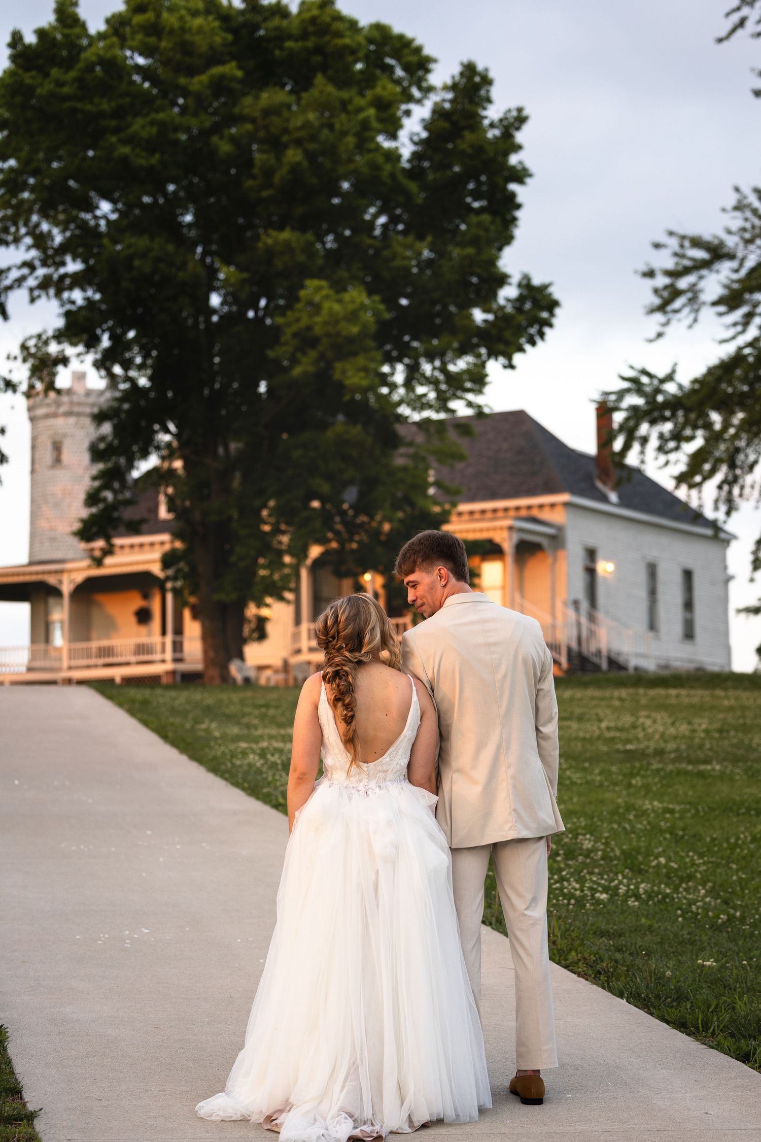 bride and groom holding hands looking at each other while walking toward venue in Boonville MO for sunset wedding portraits on wedding day