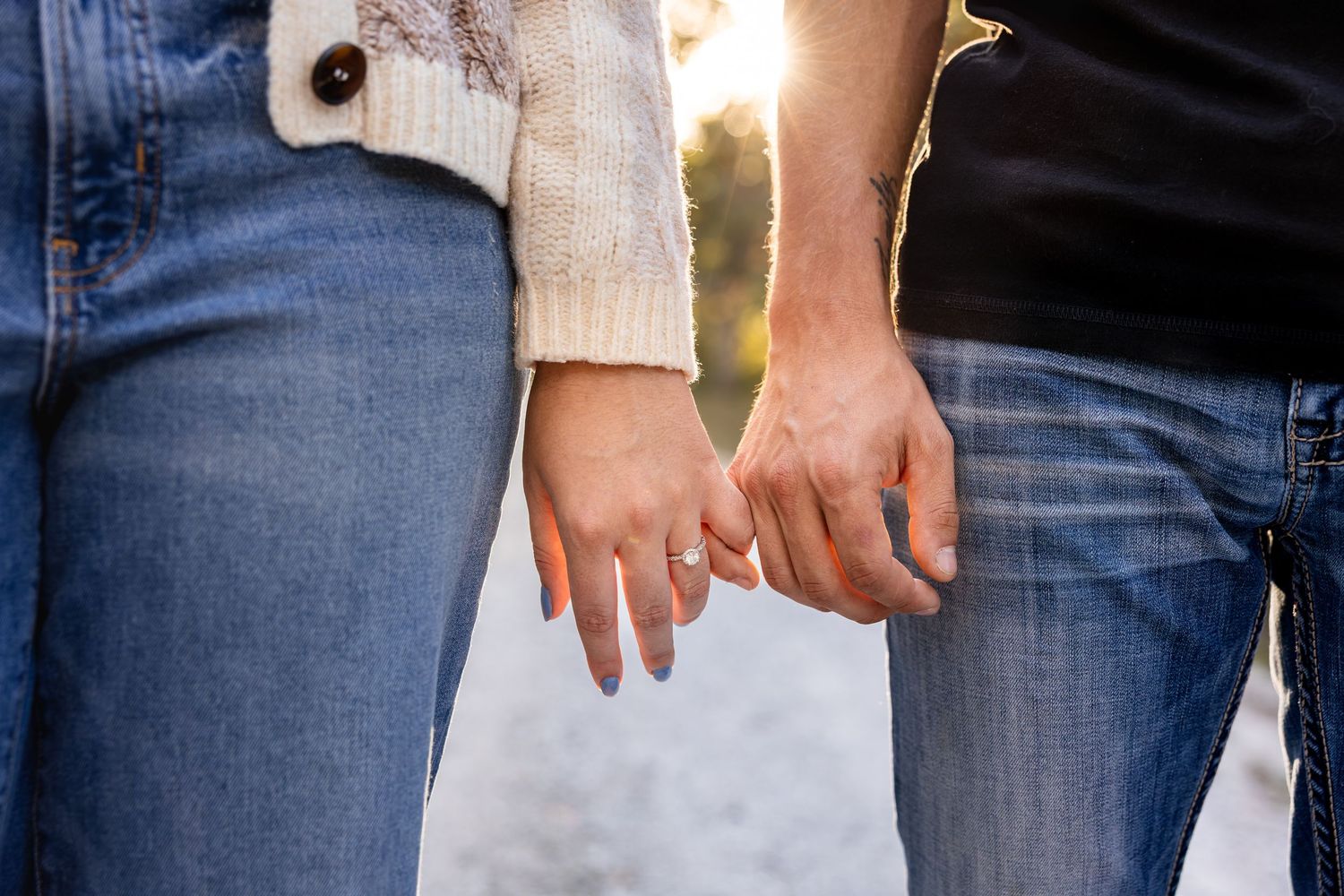 man and woman holding pinkies together during sunset engagement photo session highlighting woman's engagement ring for detail photo in MO