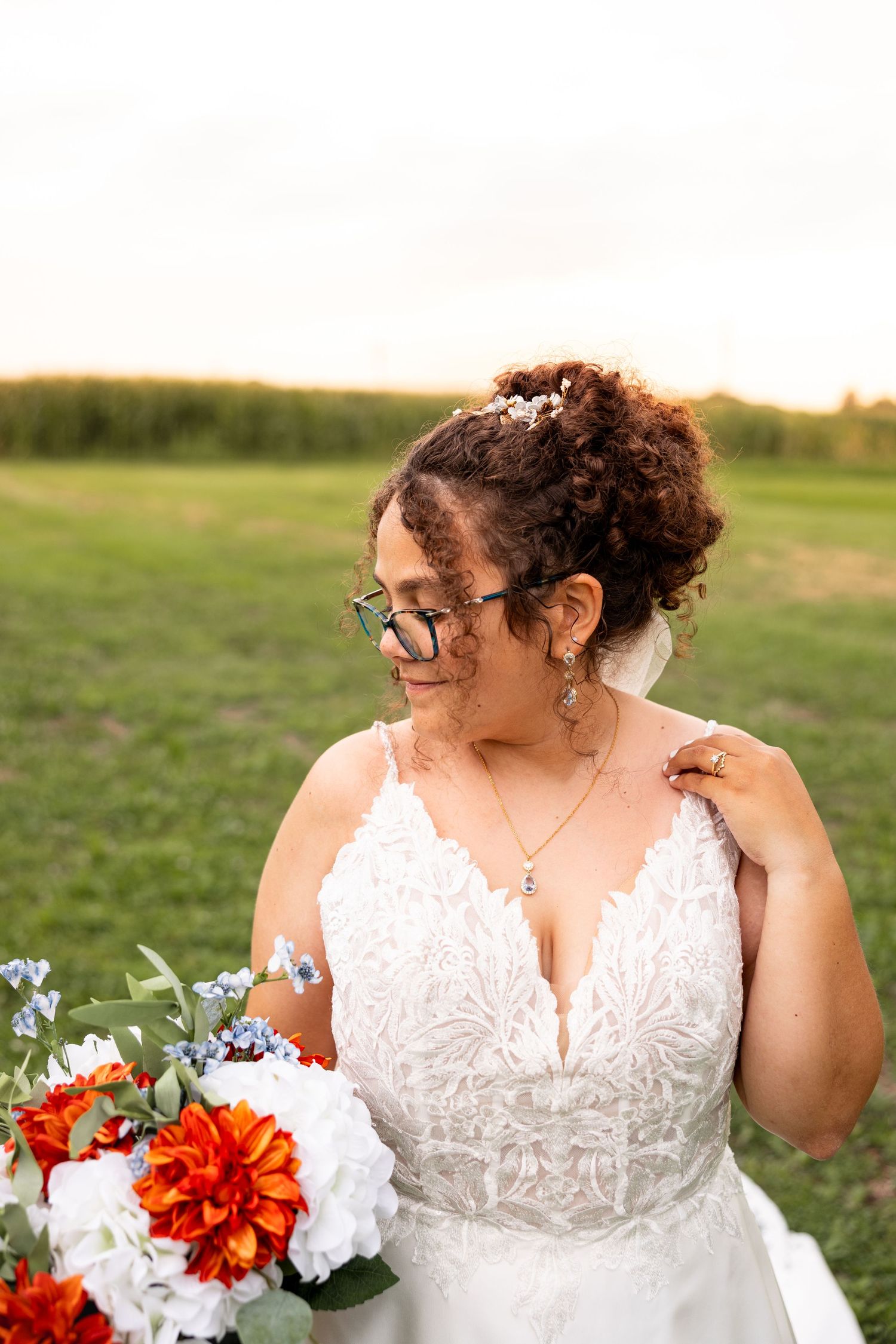 bride resting hand on her shoulder and holding bouquet during bridal photos on wedding day in Moberly MO