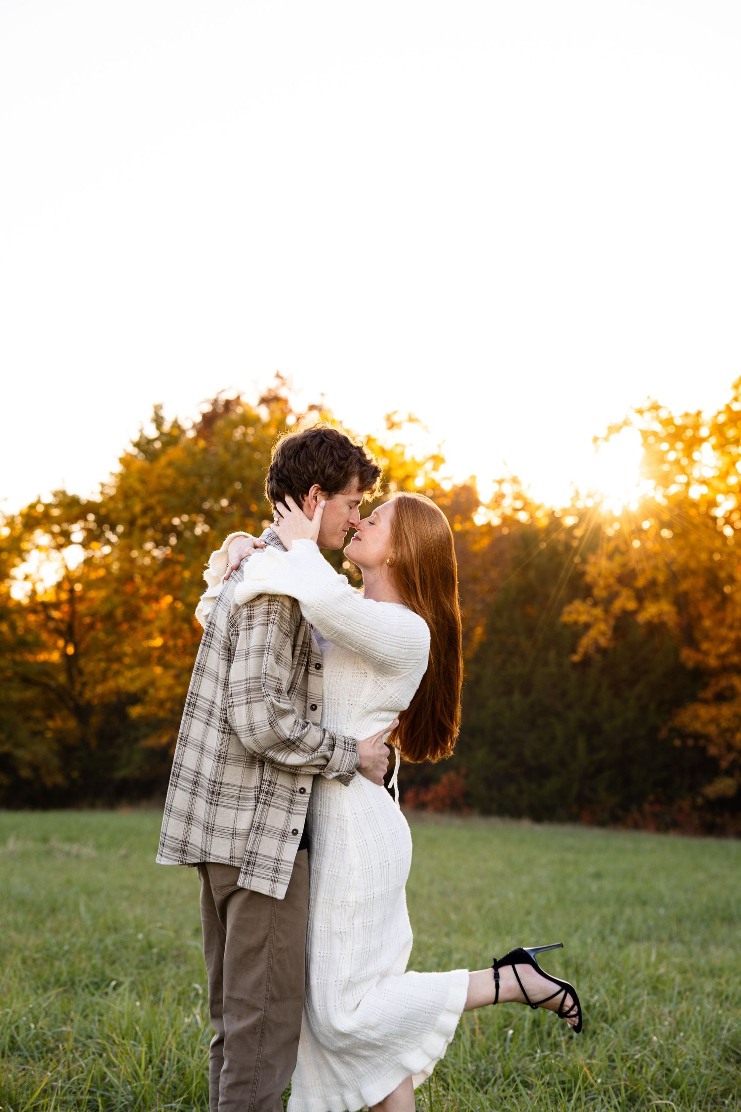 bride holding man's face and man holding her waist and kissing during sunset photos in field near Moberly MO