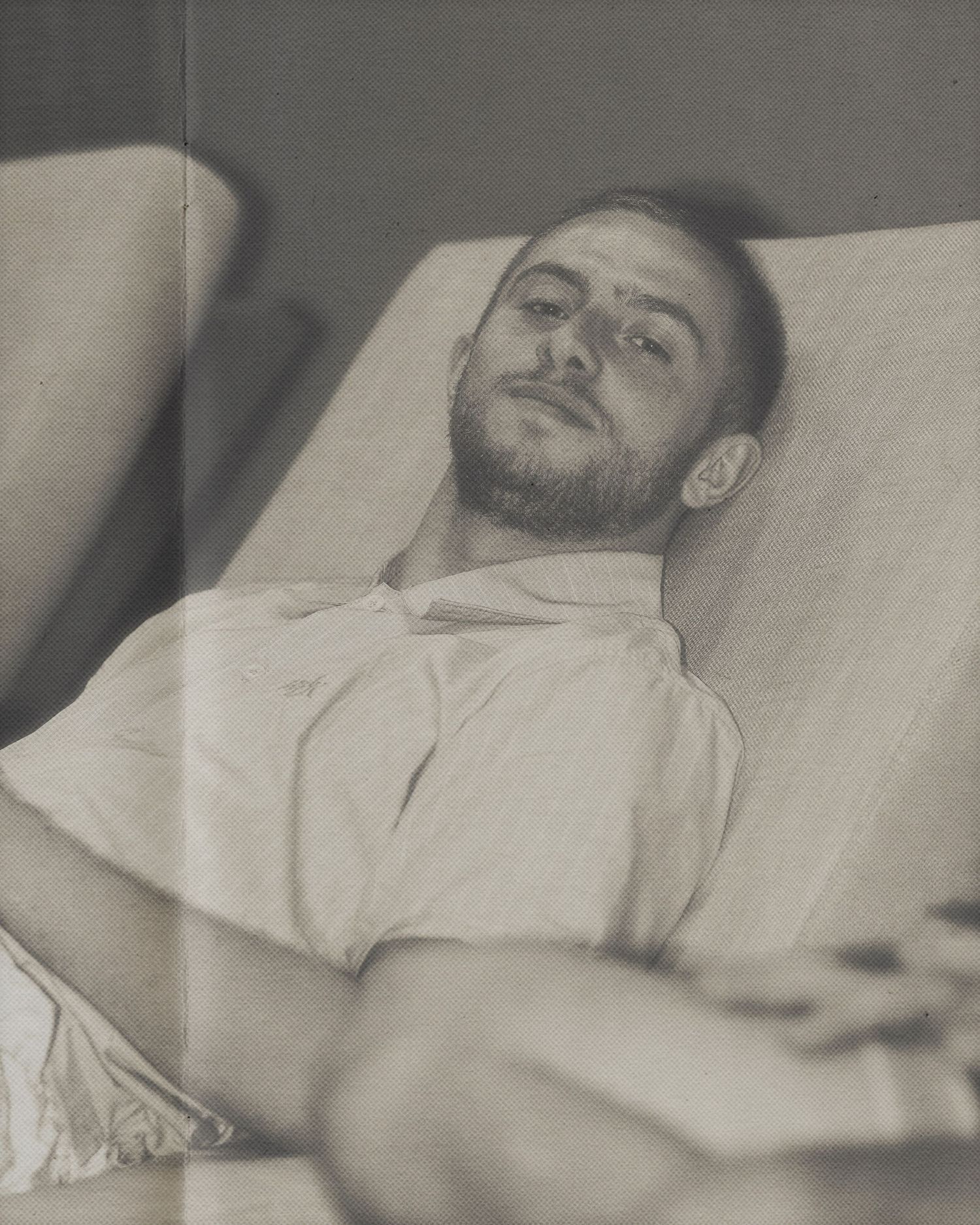 Black and white portrait of someone resting on white bedding.