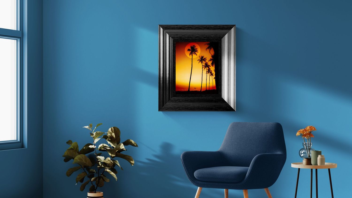 Framed tropical sunset painting with palm trees on a blue wall above a navy armchair in a modern living room.