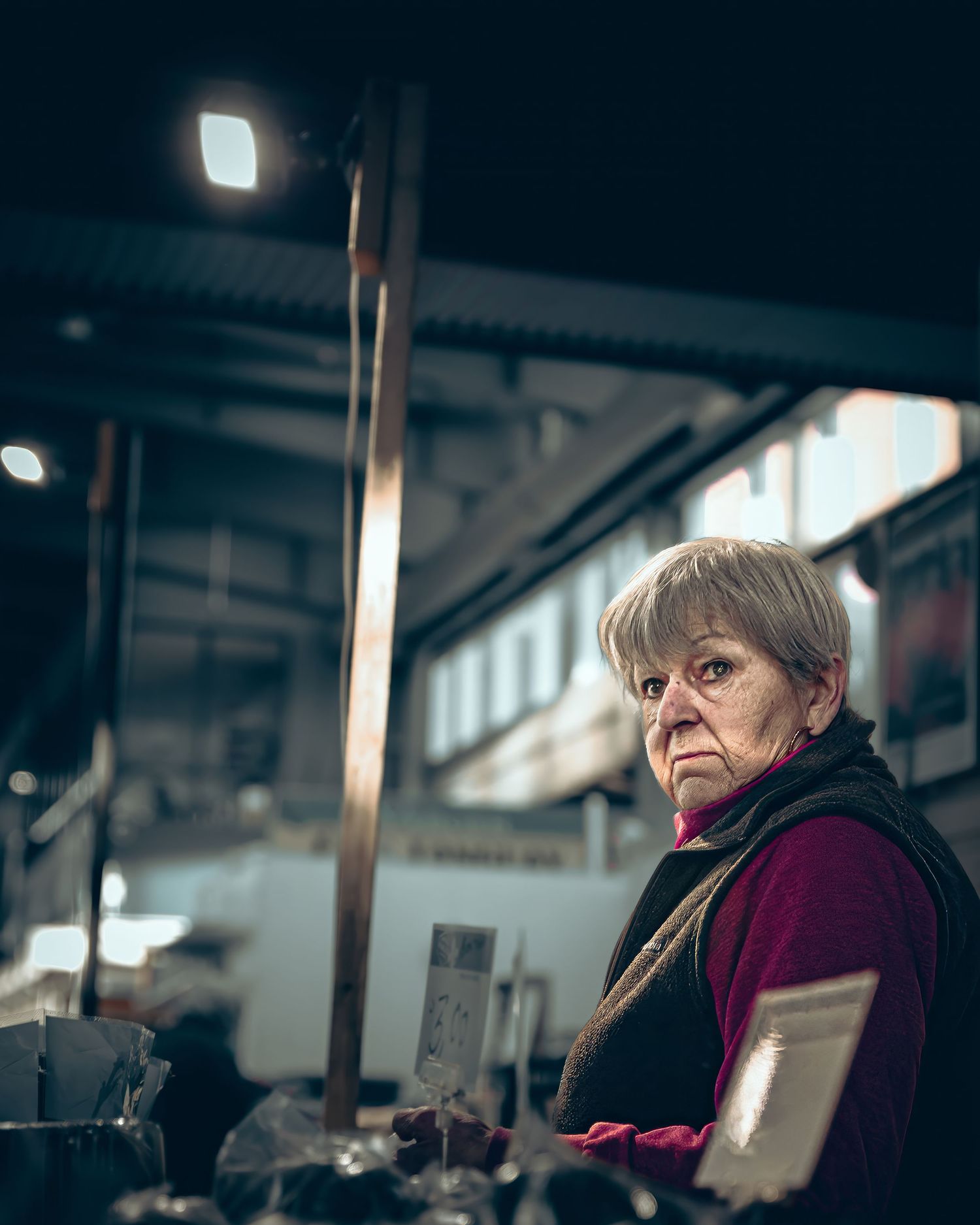Person in burgundy sweater working at computer station in industrial office setting.