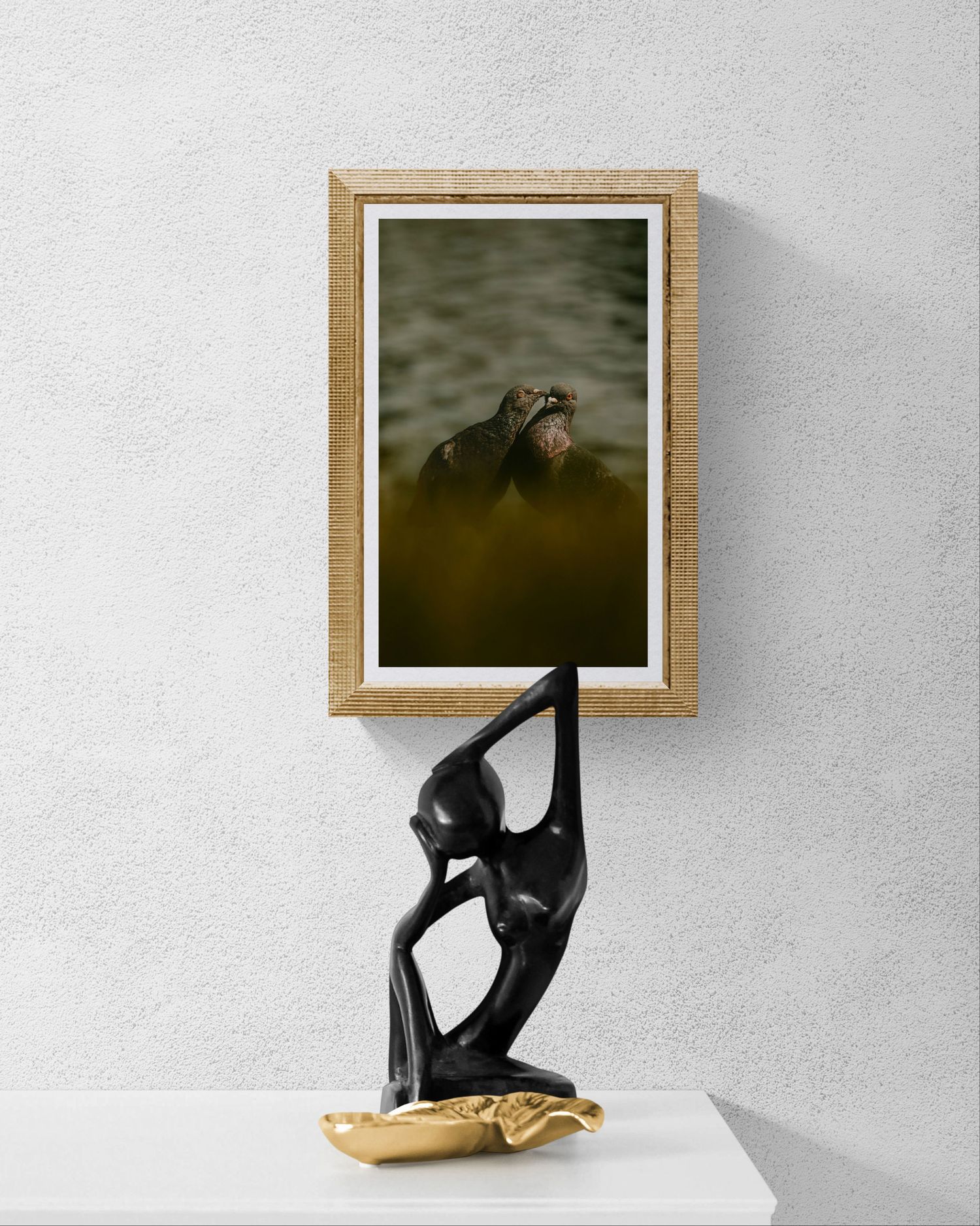 A framed wildlife photo of a hippo in water displayed above a sleek black abstract dancer sculpture on a white shelf.