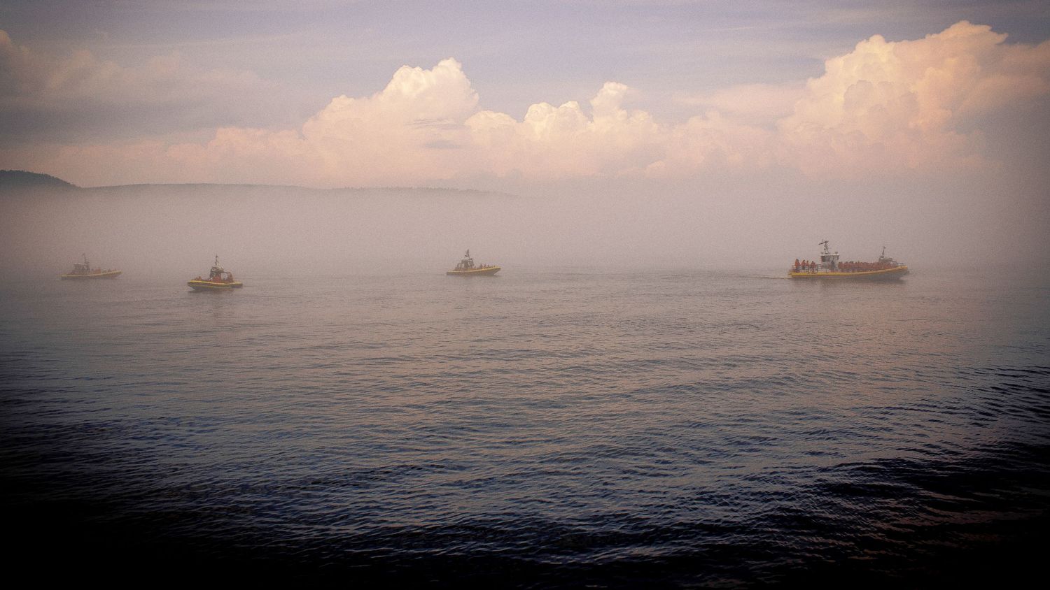 Misty seascape panorama with ships on the horizon during a peaceful sunset.