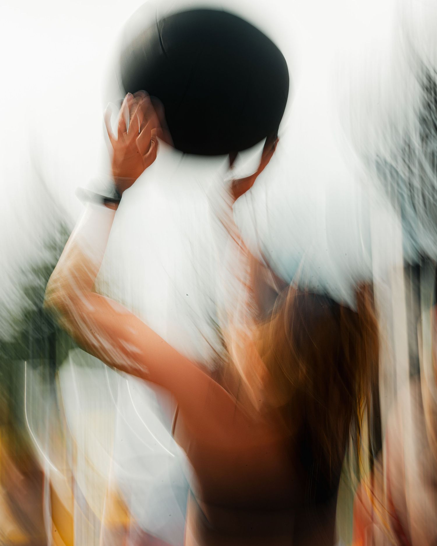 Abstract motion blur photograph captures movement in warm tones against white background.