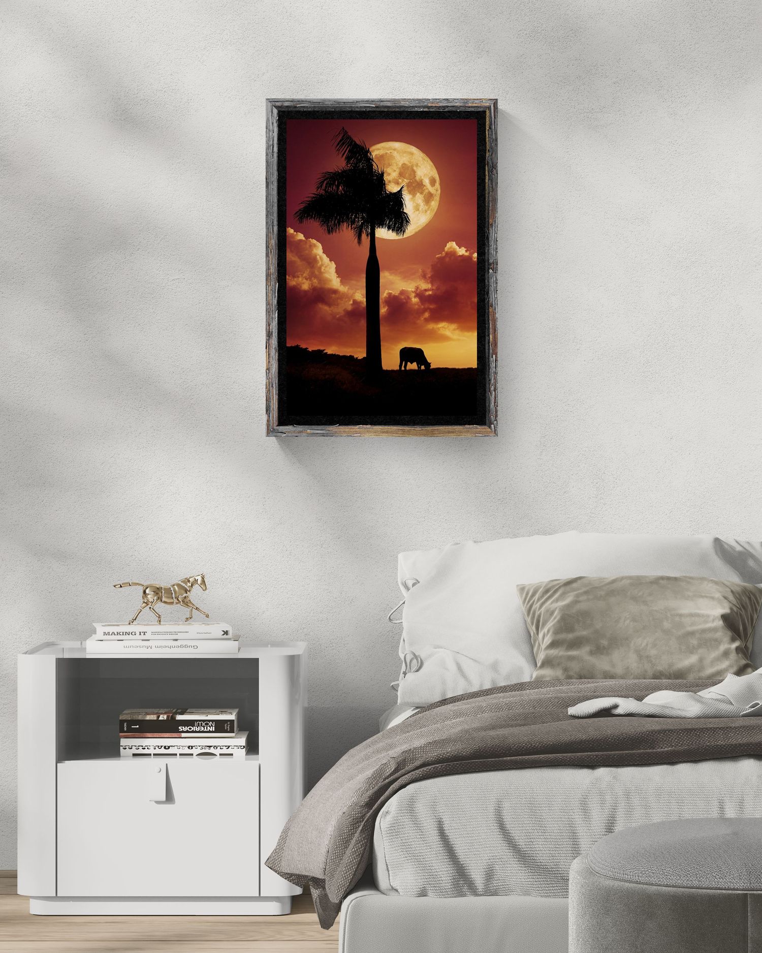 Framed elephant silhouette wall art with red sunset and full moon, displayed above a white nightstand in a cozy bedroom.