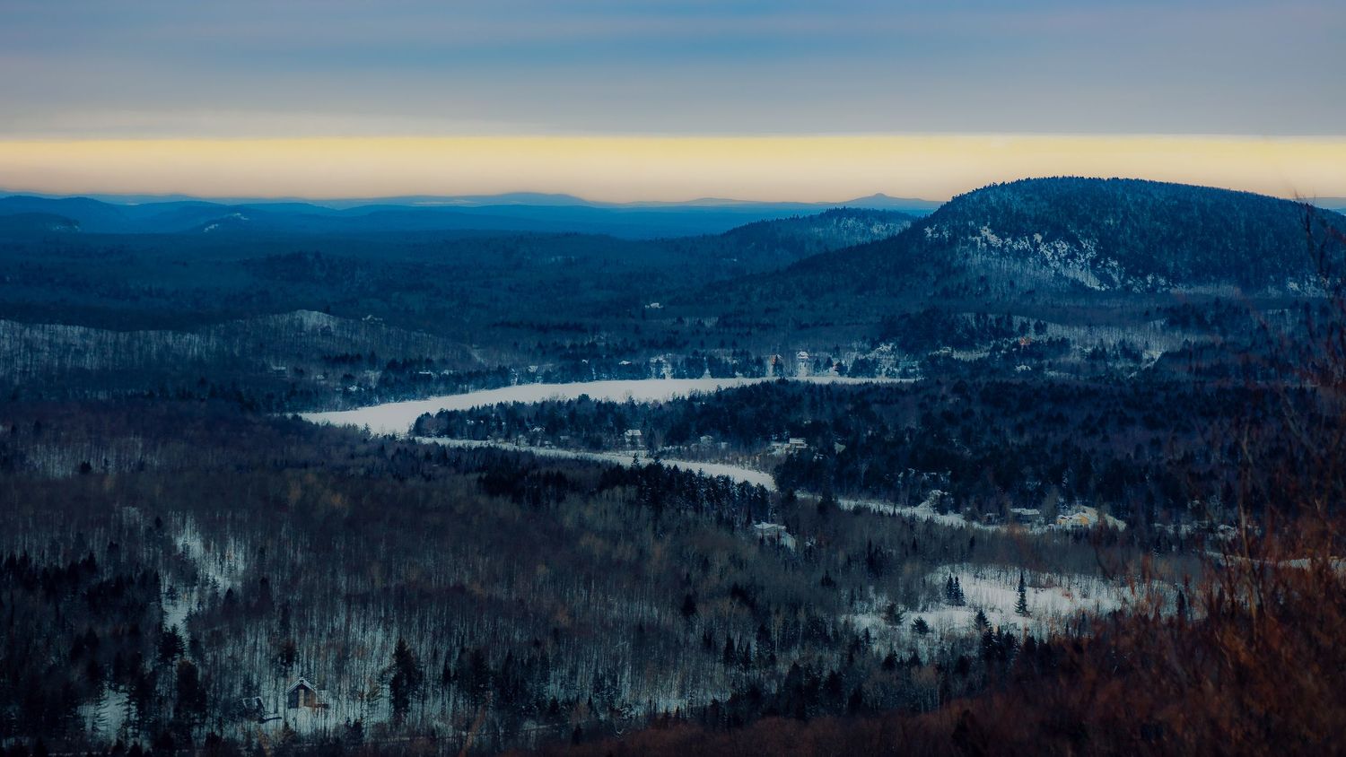 Scenic mountain panorama with snow-capped peaks and forested slopes under a bright blue sky.