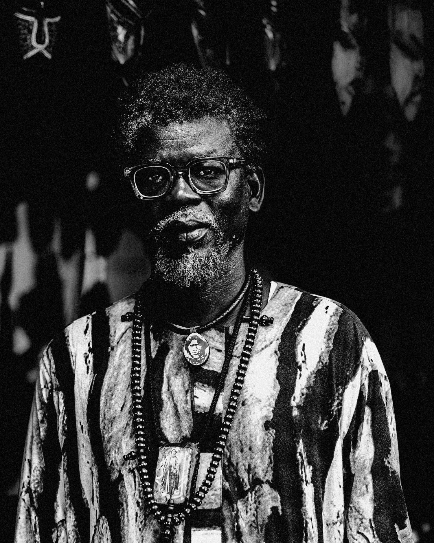A series of black and white portraits showing the same person wearing round glasses and a striped shirt in different poses.