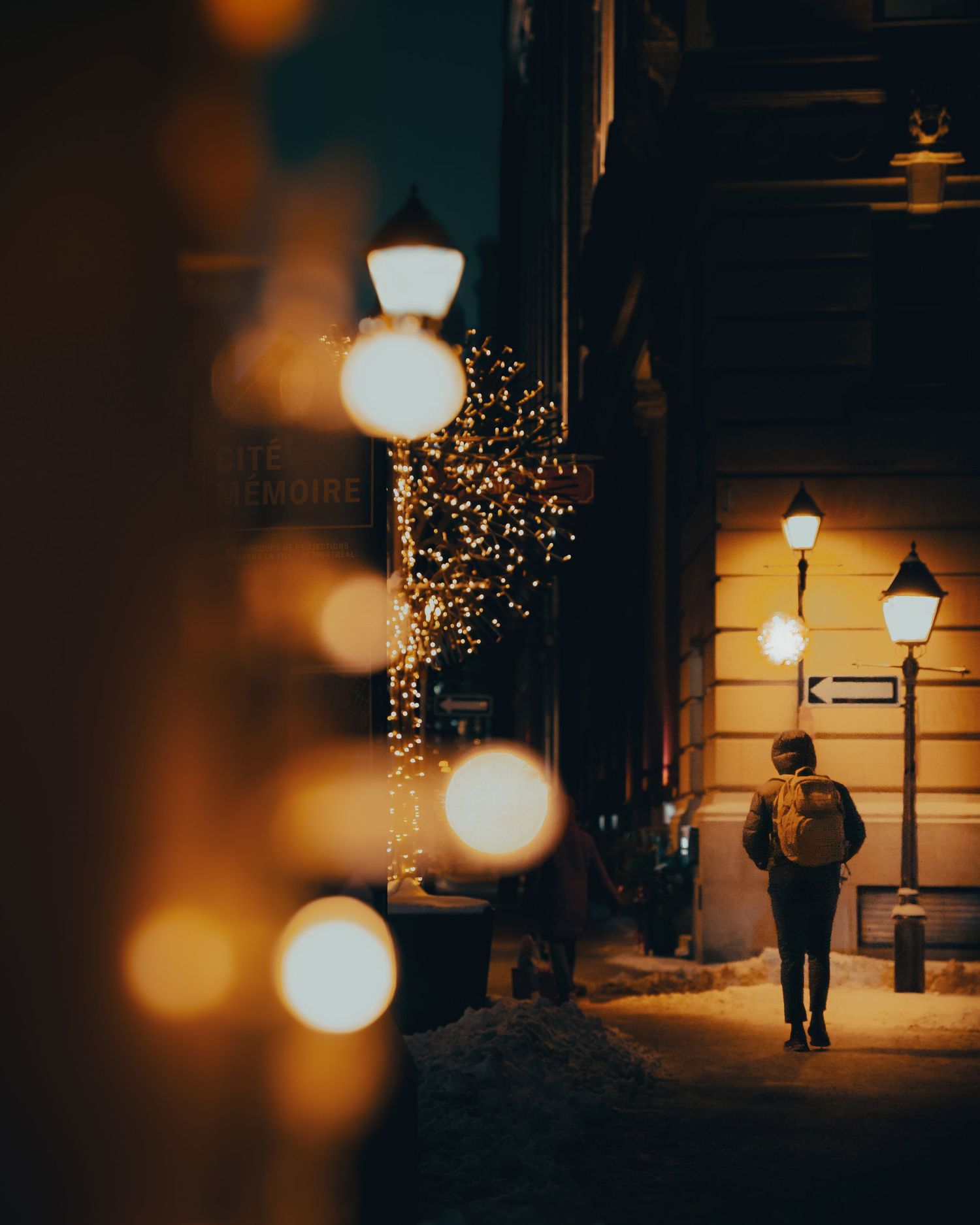 Atmospheric nighttime street scene with glowing bokeh lights and street lamps.
