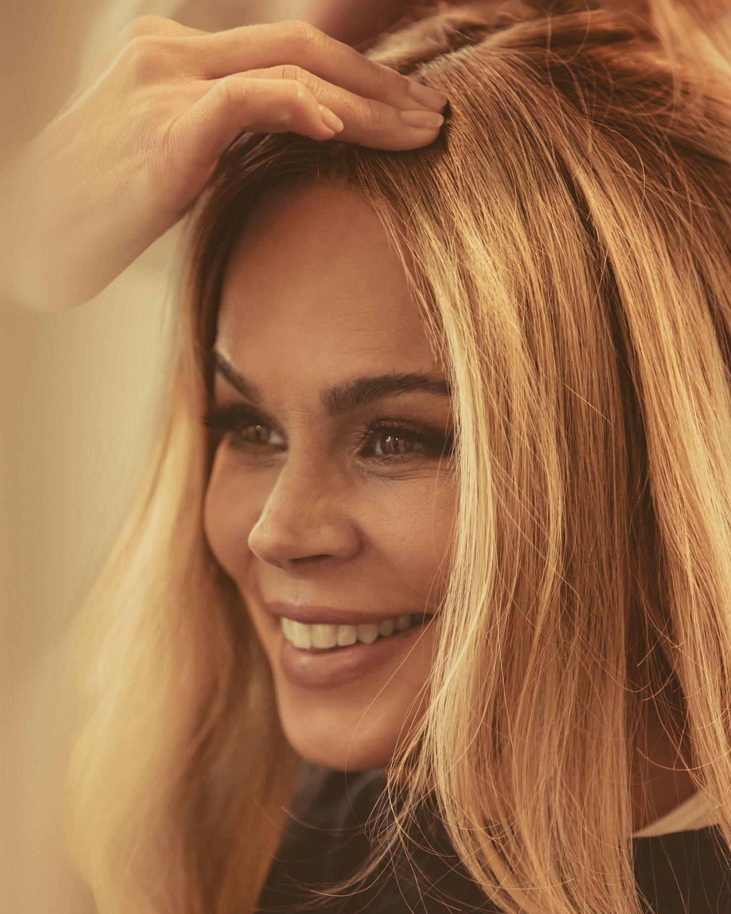 Warm-toned beauty photography showing styled blonde hair with natural lighting.