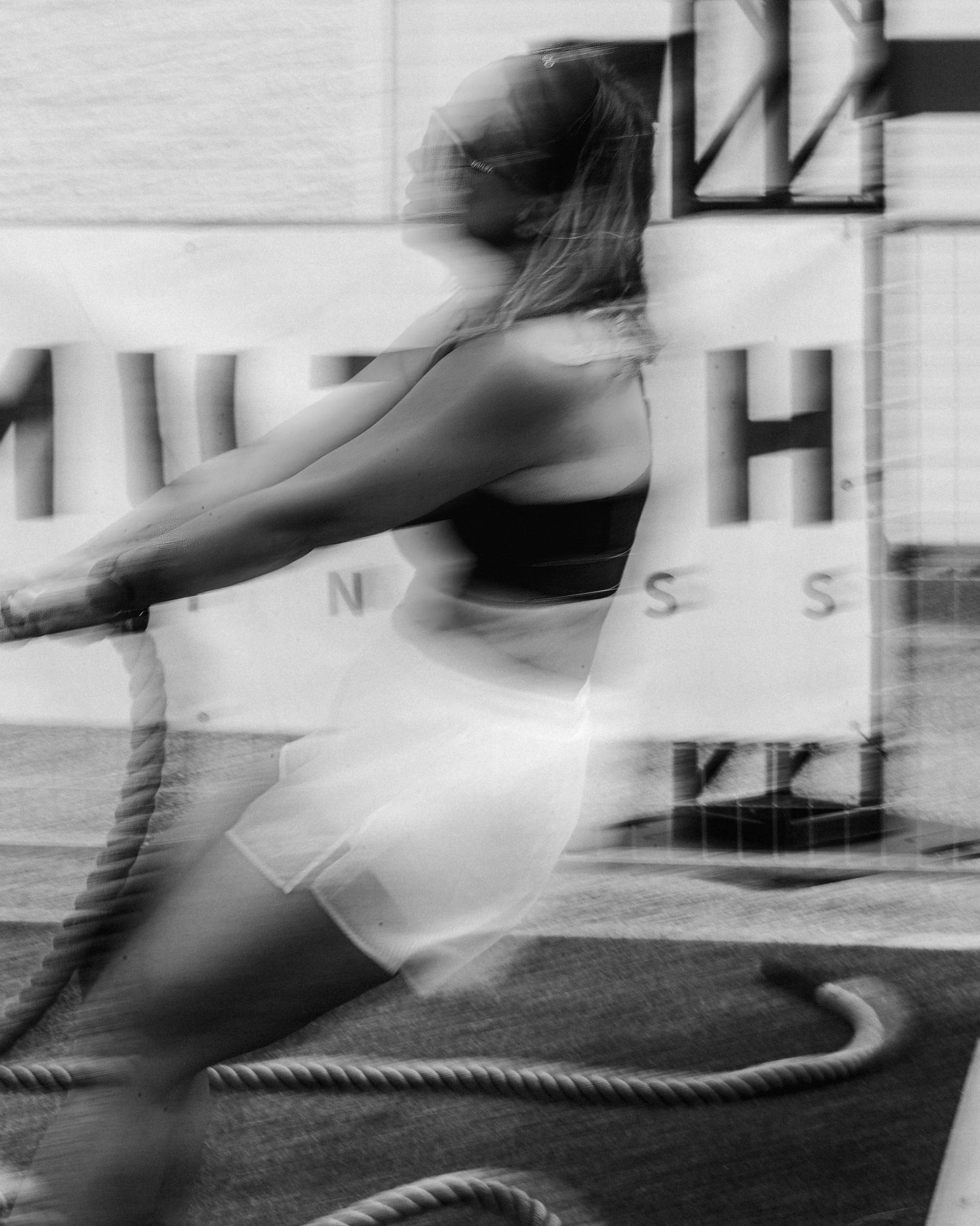 Black and white motion blur captures athletic movement against architectural background.