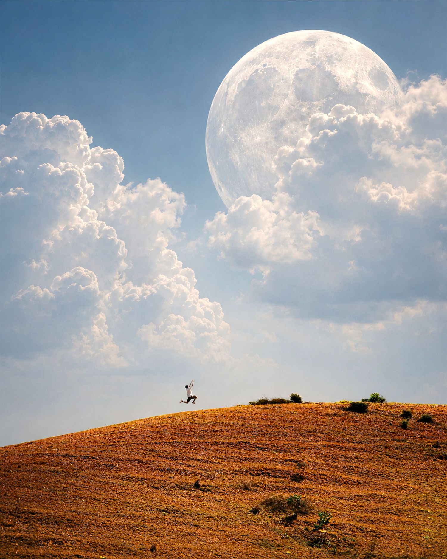 A person stands atop a golden hill beneath a giant moon and dramatic clouds in a surreal landscape.