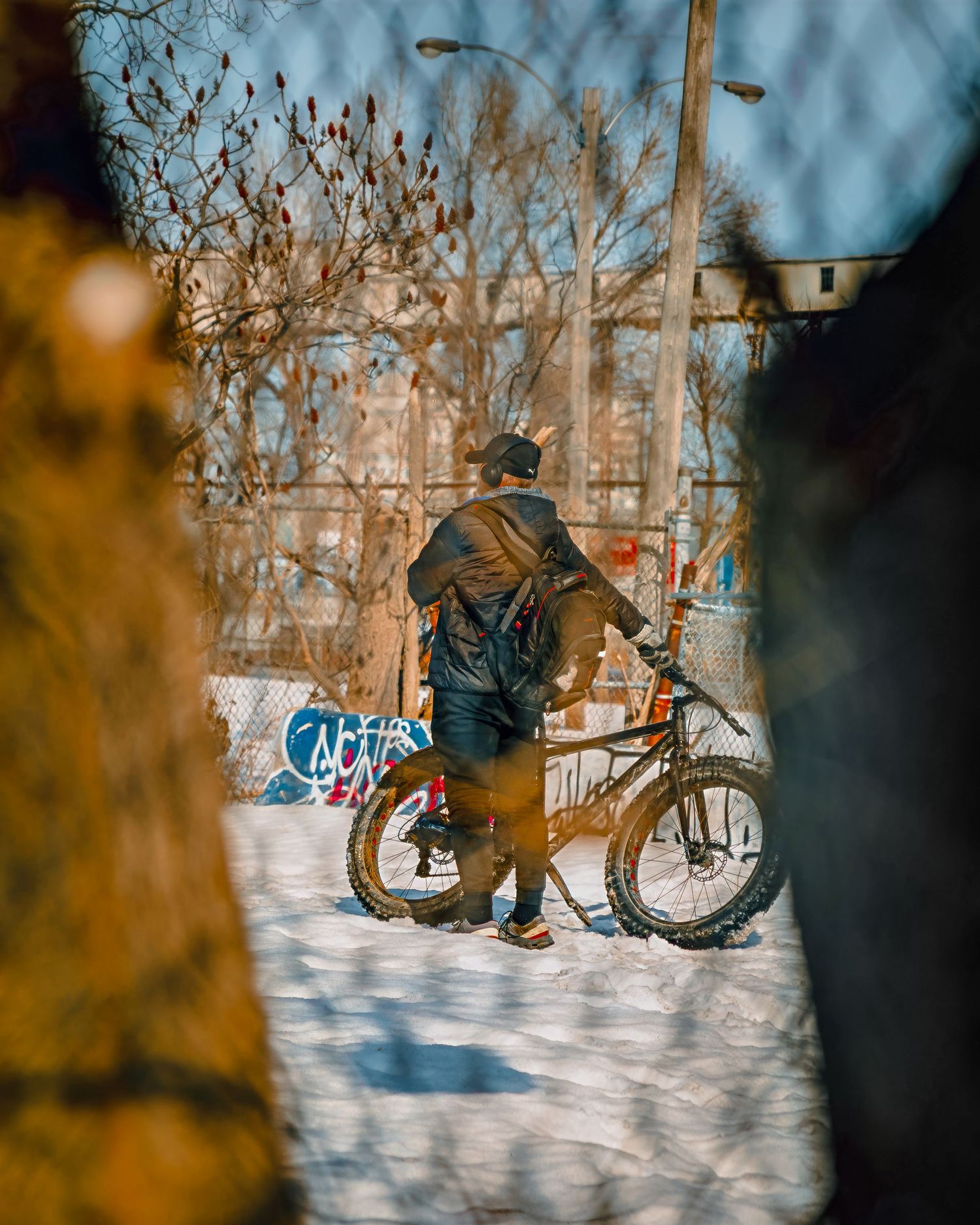 Winter scene of cyclists riding through snowy terrain with trees in the background.