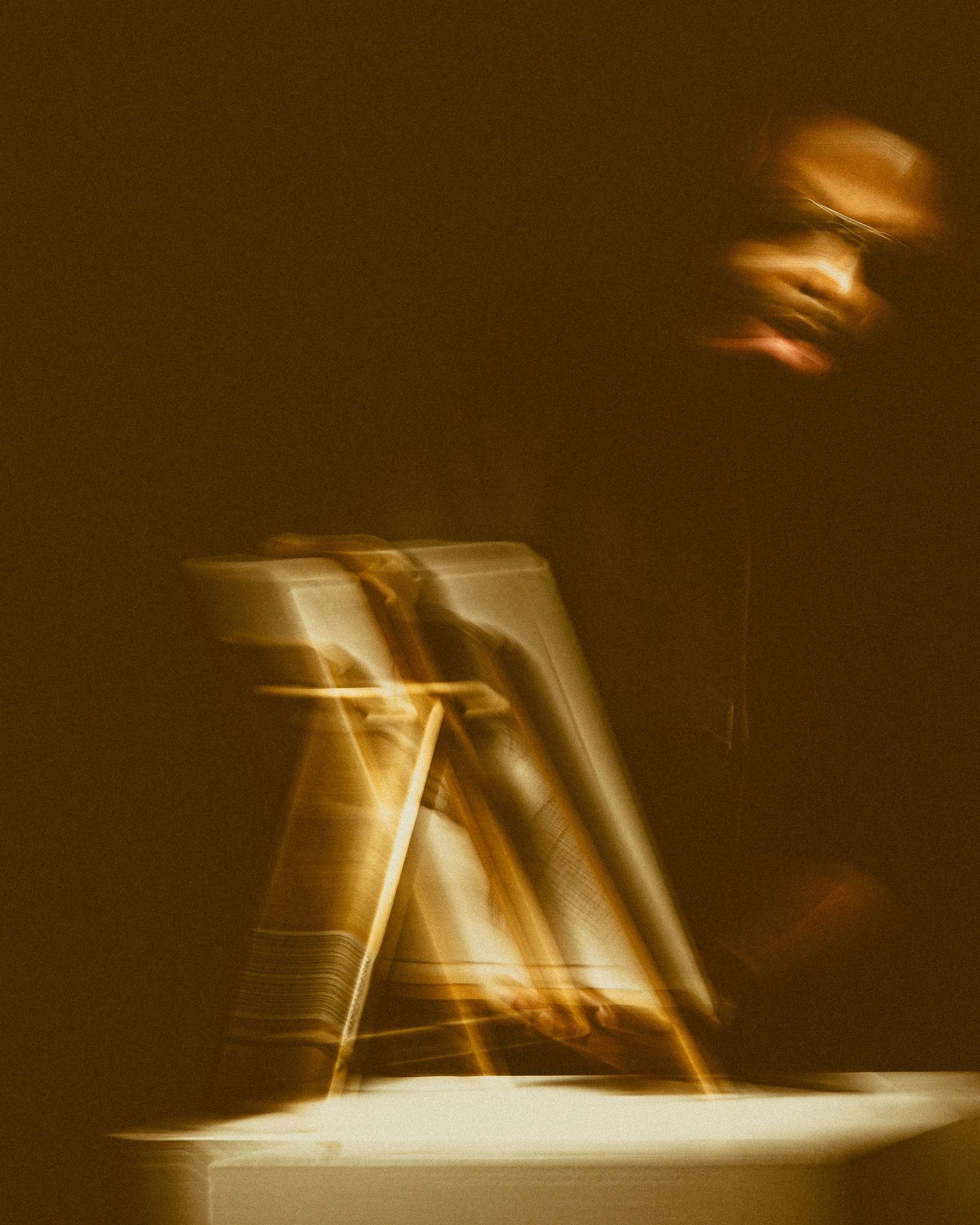 A blurred sepia-toned abstract motion photo showing ghostly figures in movement across a dark background.
