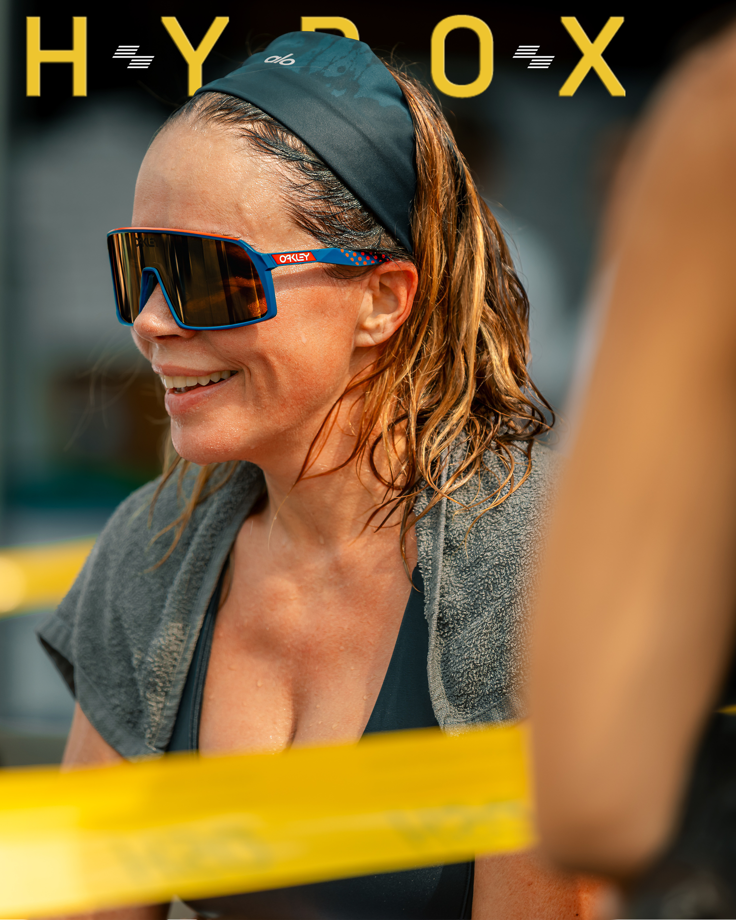 Athletic woman in sunglasses and headband smiling outdoors with Hyox text overlay.