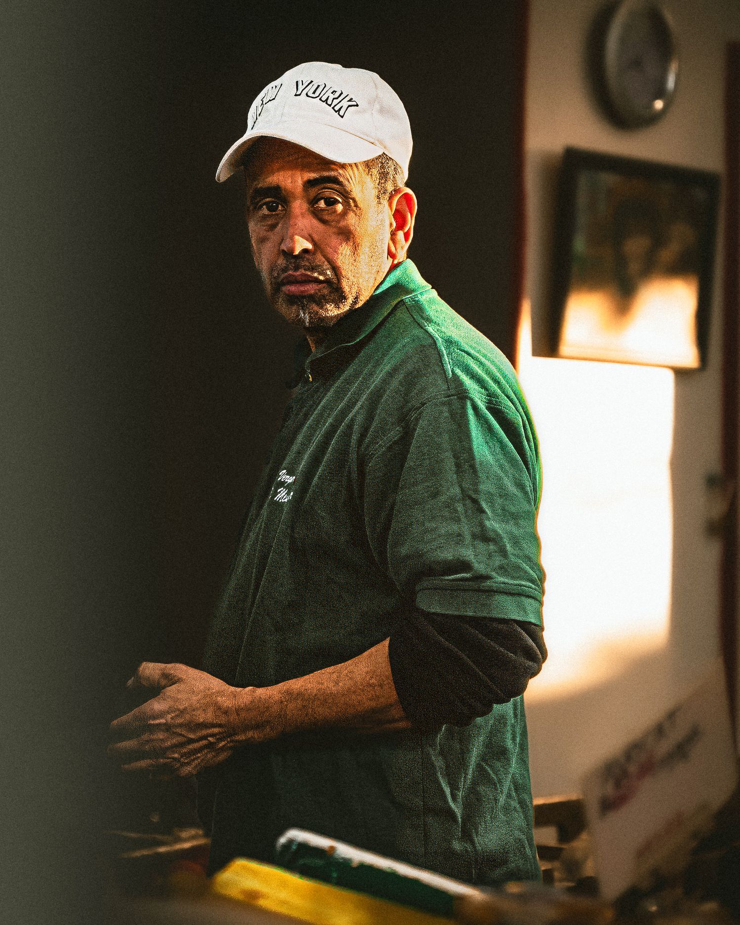 Person in green jacket and baseball cap moving through dimly lit indoor space.