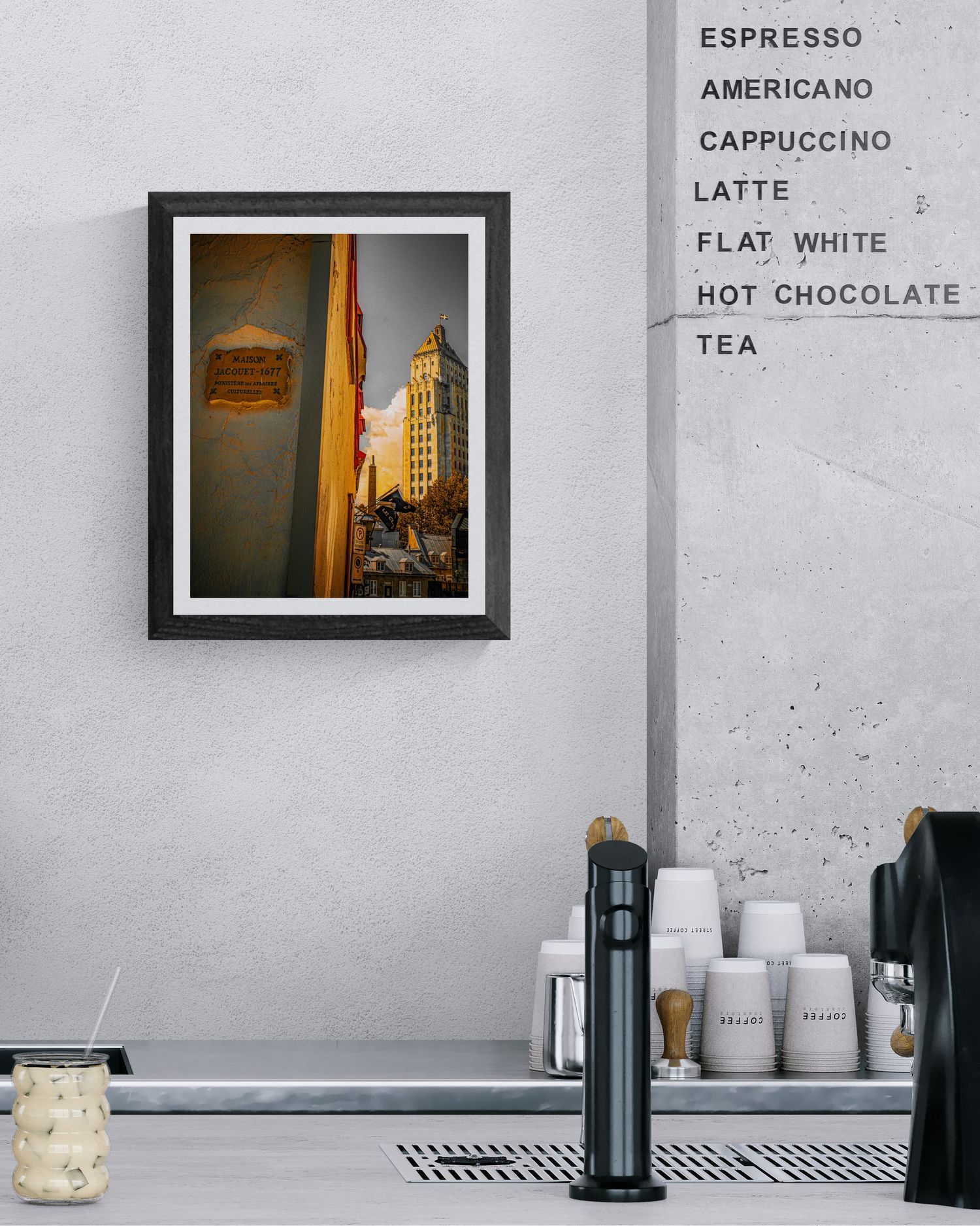 Framed urban architecture photo on cafe wall beside a handwritten coffee menu listing espresso, latte, and tea.