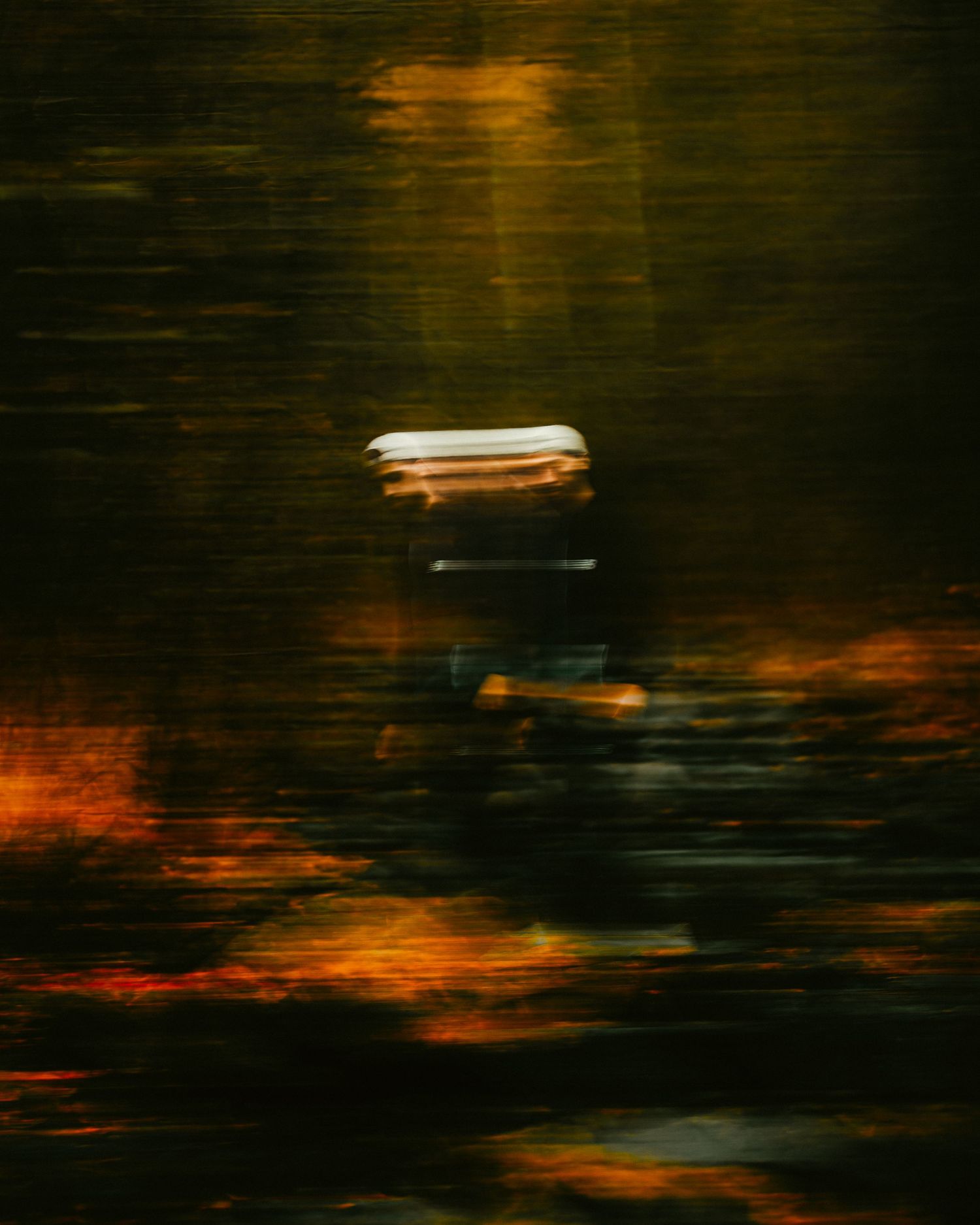 Abstract dark art with orange and black reflections creating a moody atmospheric effect on a reflective surface.