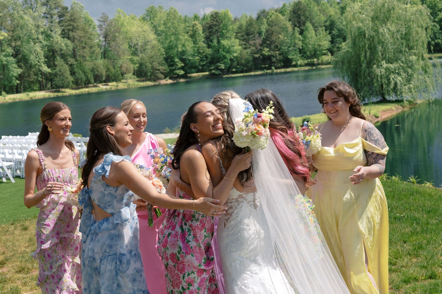 Colorfully dressed Bridesmaids joyfully surrounding the bride in a group hug