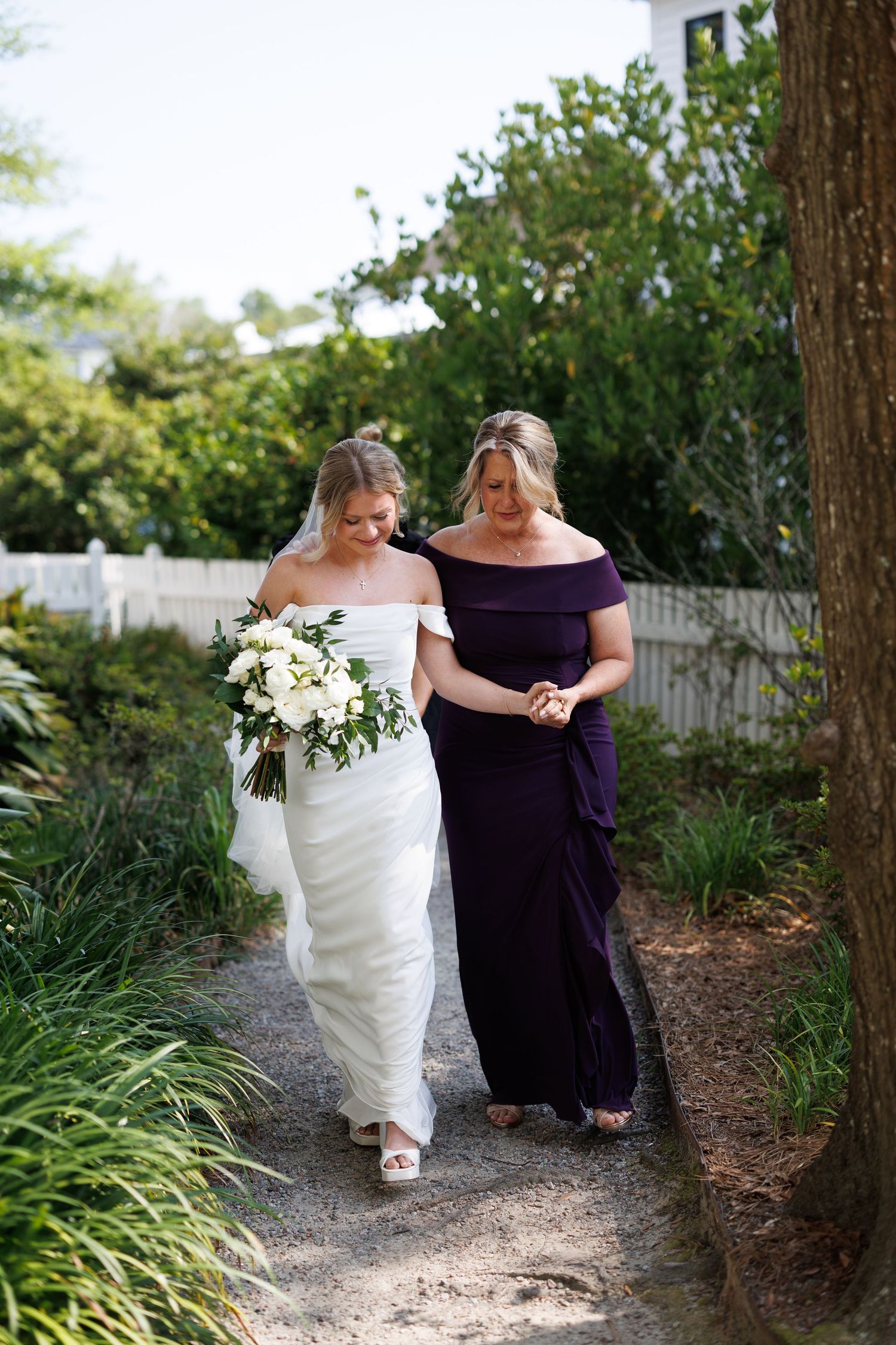 Bride with her mother walking down the path — beautifully intimate, feminine, and emotional