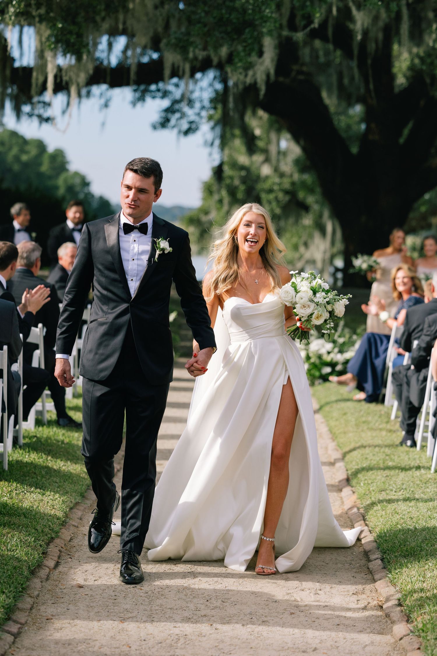 A wedding recessional with a joyful Bride and Groom walking down a southern wedding venue at Middleton Place