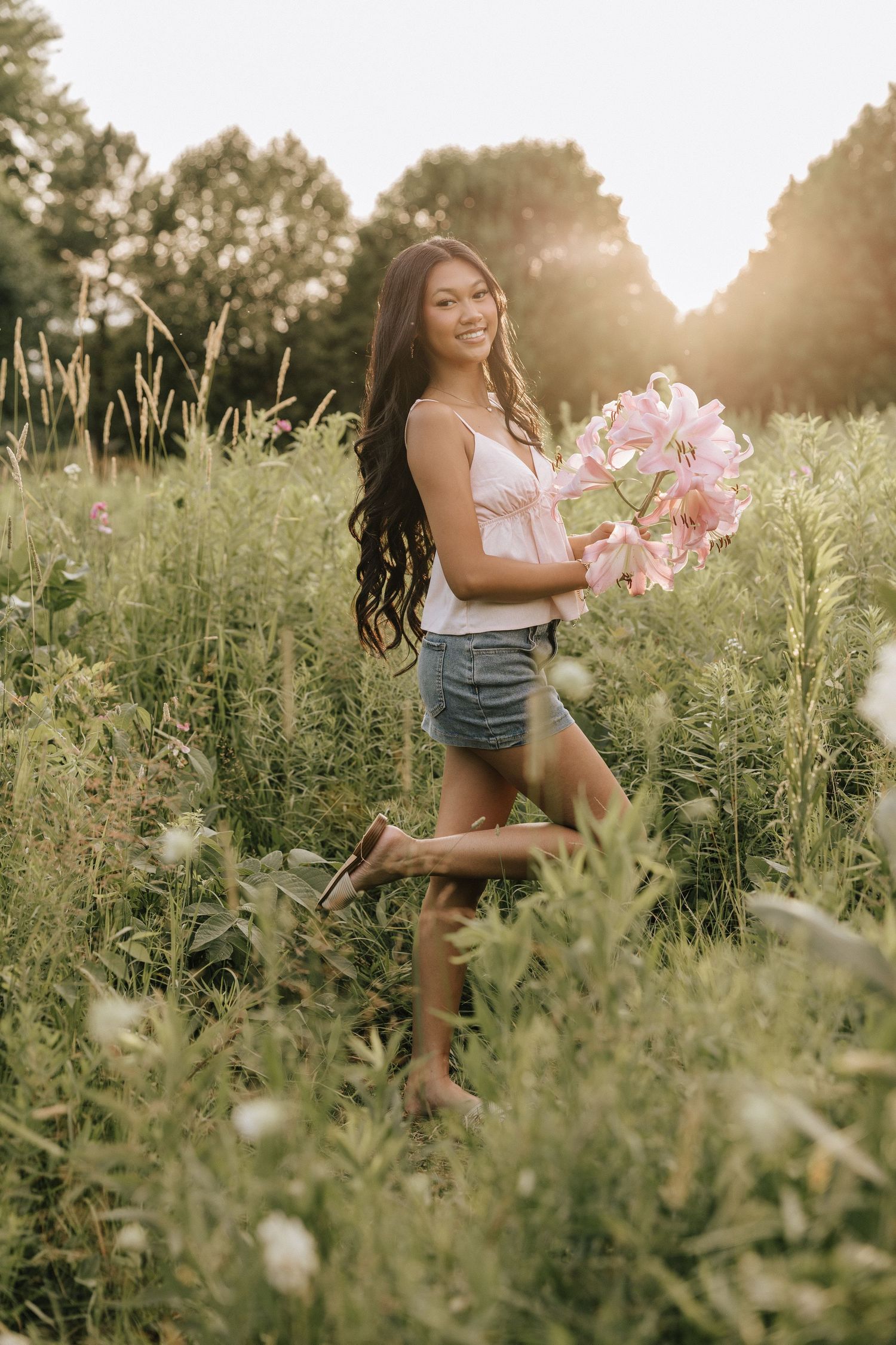 Someone enjoying a summer day in a field of wildflowers during golden hour sunset lighting.