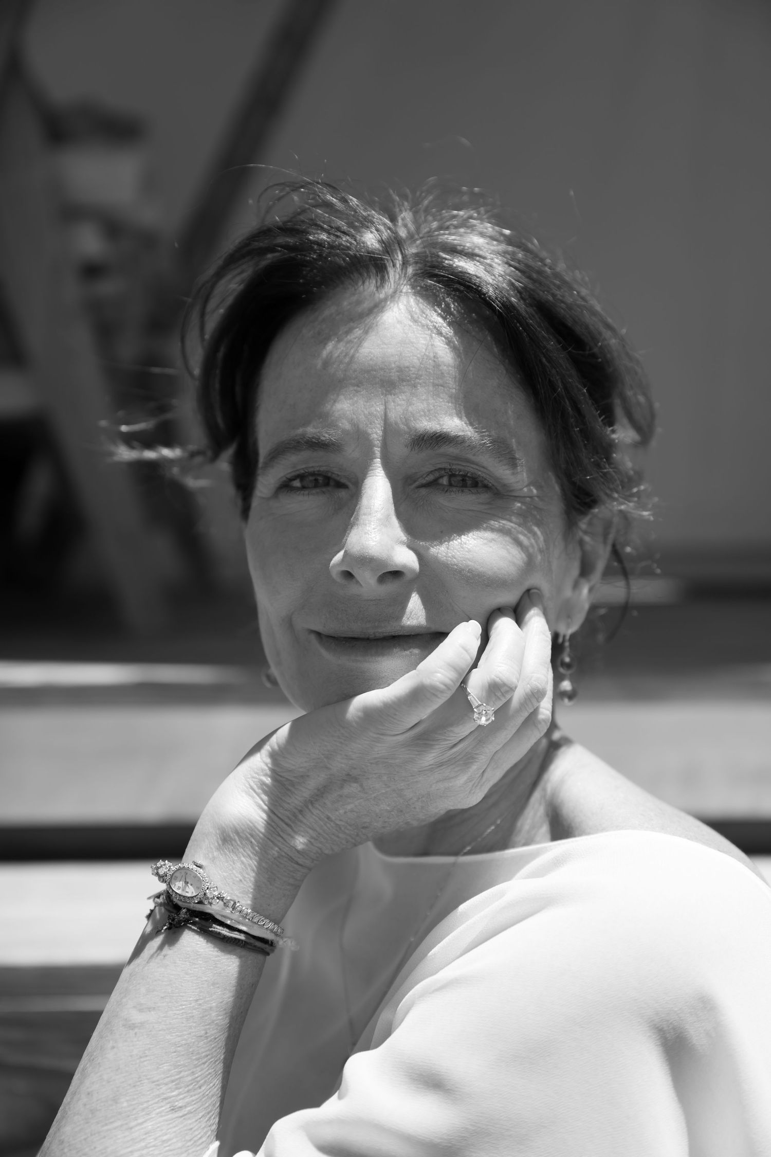 Black and white portrait of a middle-aged woman resting her chin on her hand, wearing a bracelet and ring.