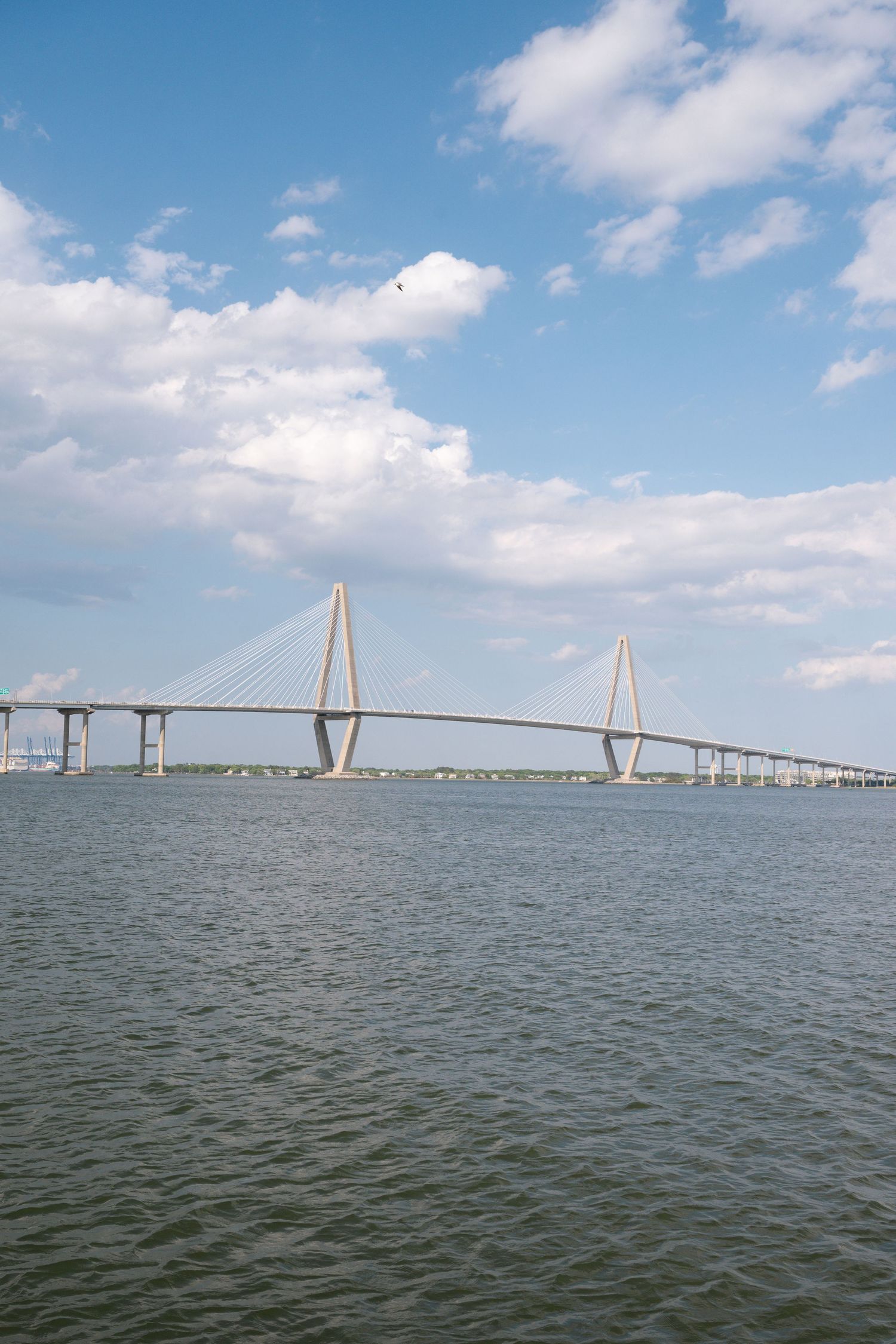 Arthur Ravenel Jr. cable-stayed bridge spanning calm blue waters under partly cloudy sky in Charleston, SC.
