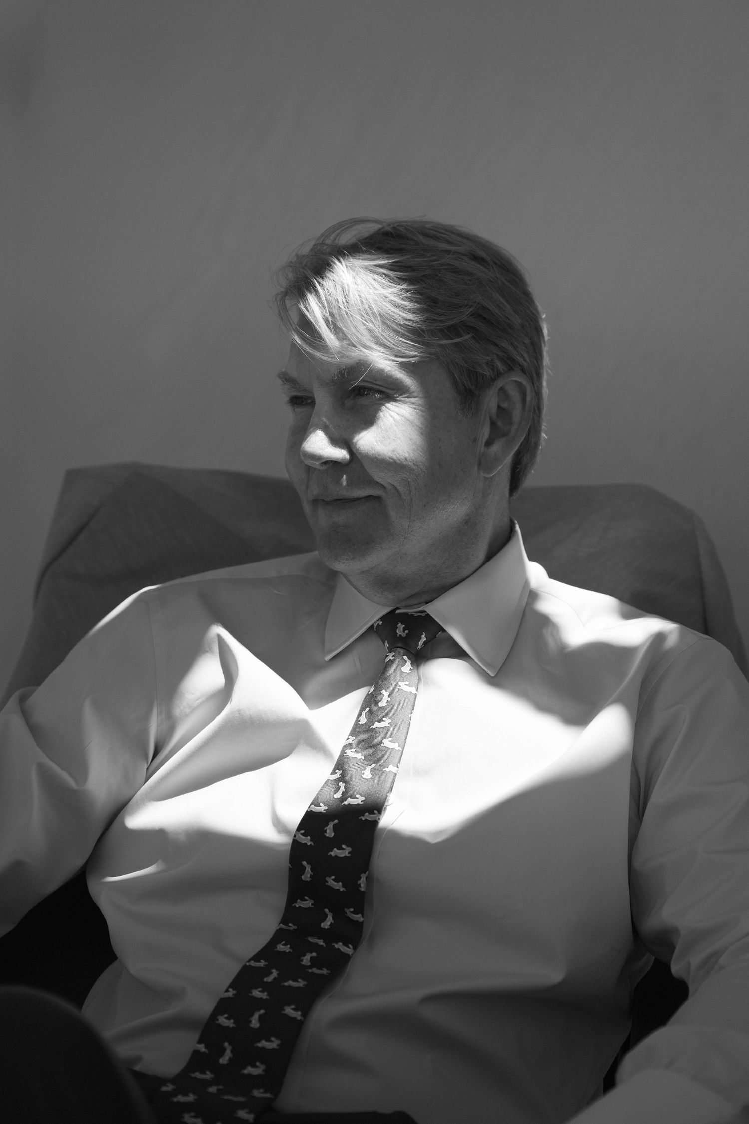 Black and white portrait of smiling middle-aged man in dress shirt and tie.