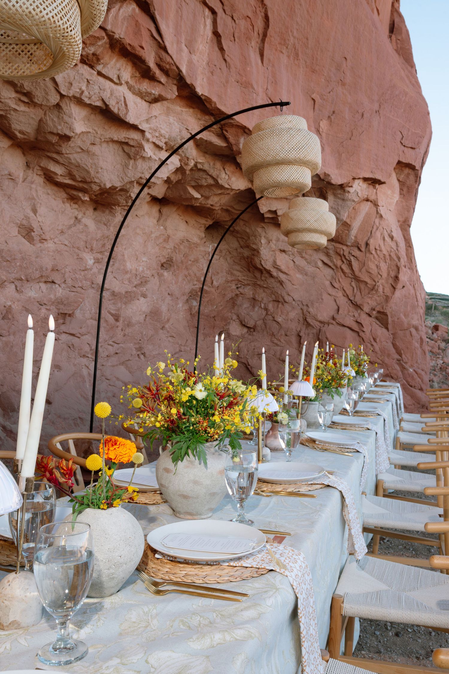 Elegant outdoor desert wedding reception table set against red rock canyon wall in Moab Utah.