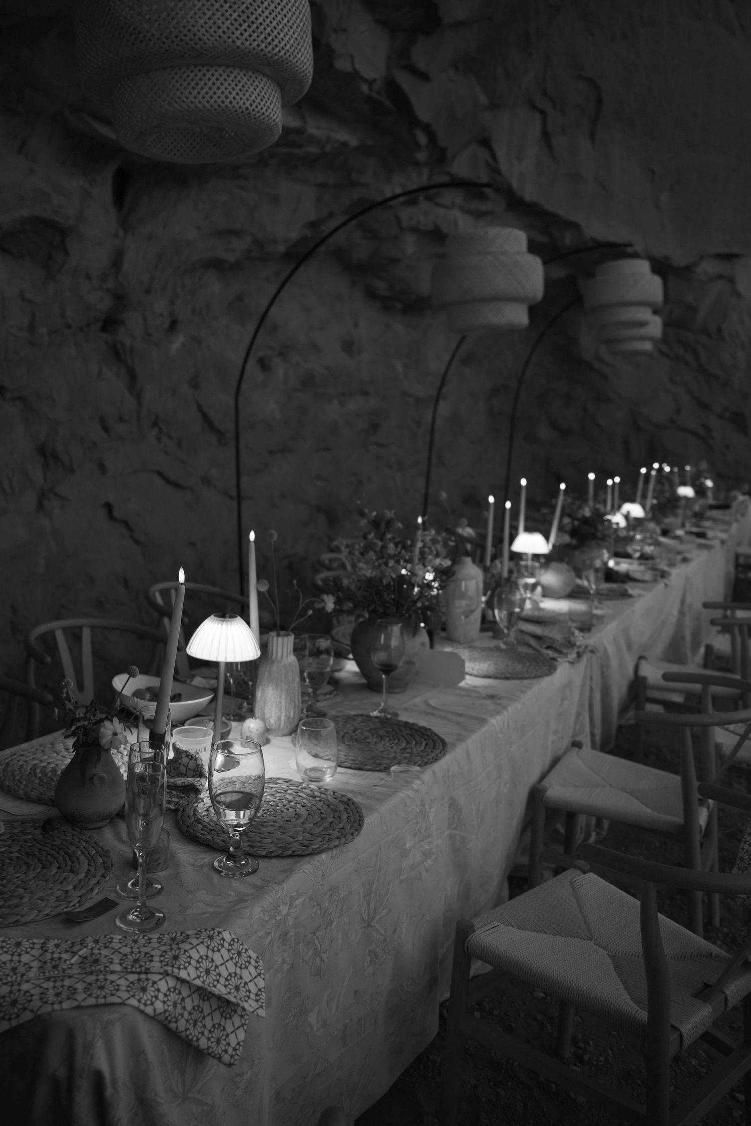 Elegant black and white long wedding reception table set in a dramatic cave with candles and lanterns.