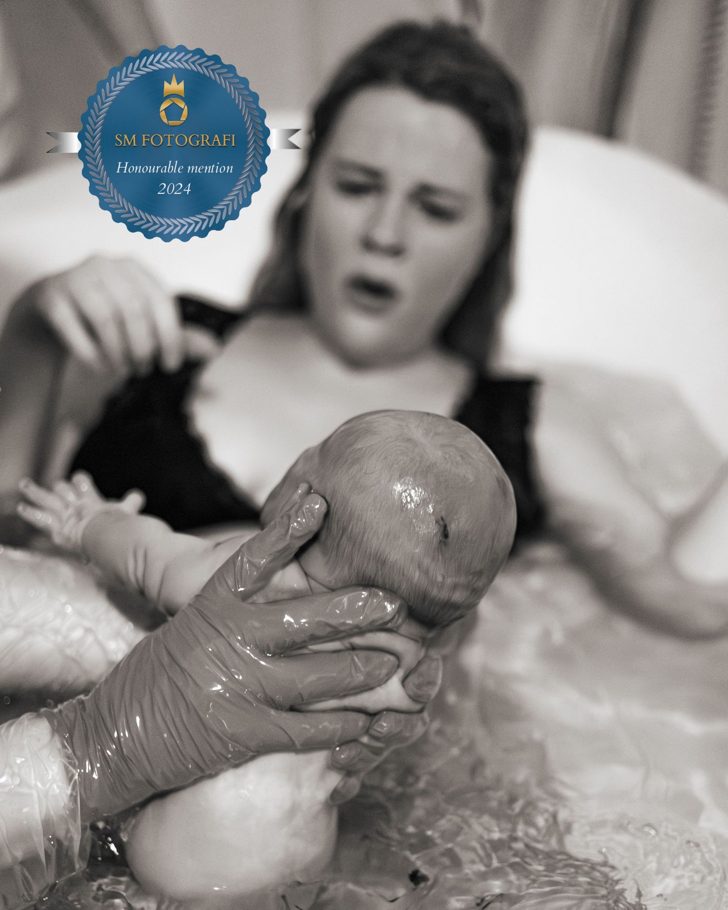 Förlossningsfoto taget på det första mötet mellan mamma och barn när bebisen lyfts upp ur vattnet. SM-finalist i SM i fotografi