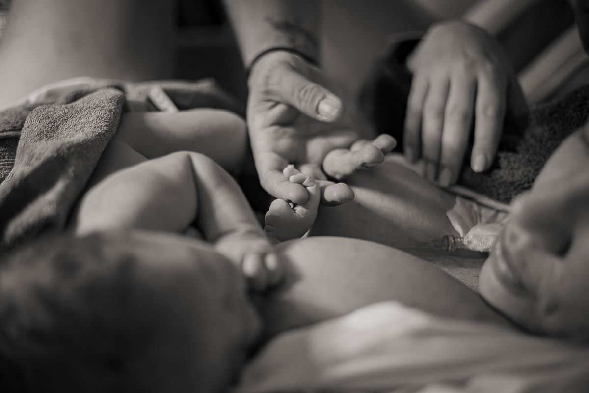 Svartvitt förlossningsfoto, St Görans i Stockholm. Närbild på liten nyfödd hand som håller pappas finger