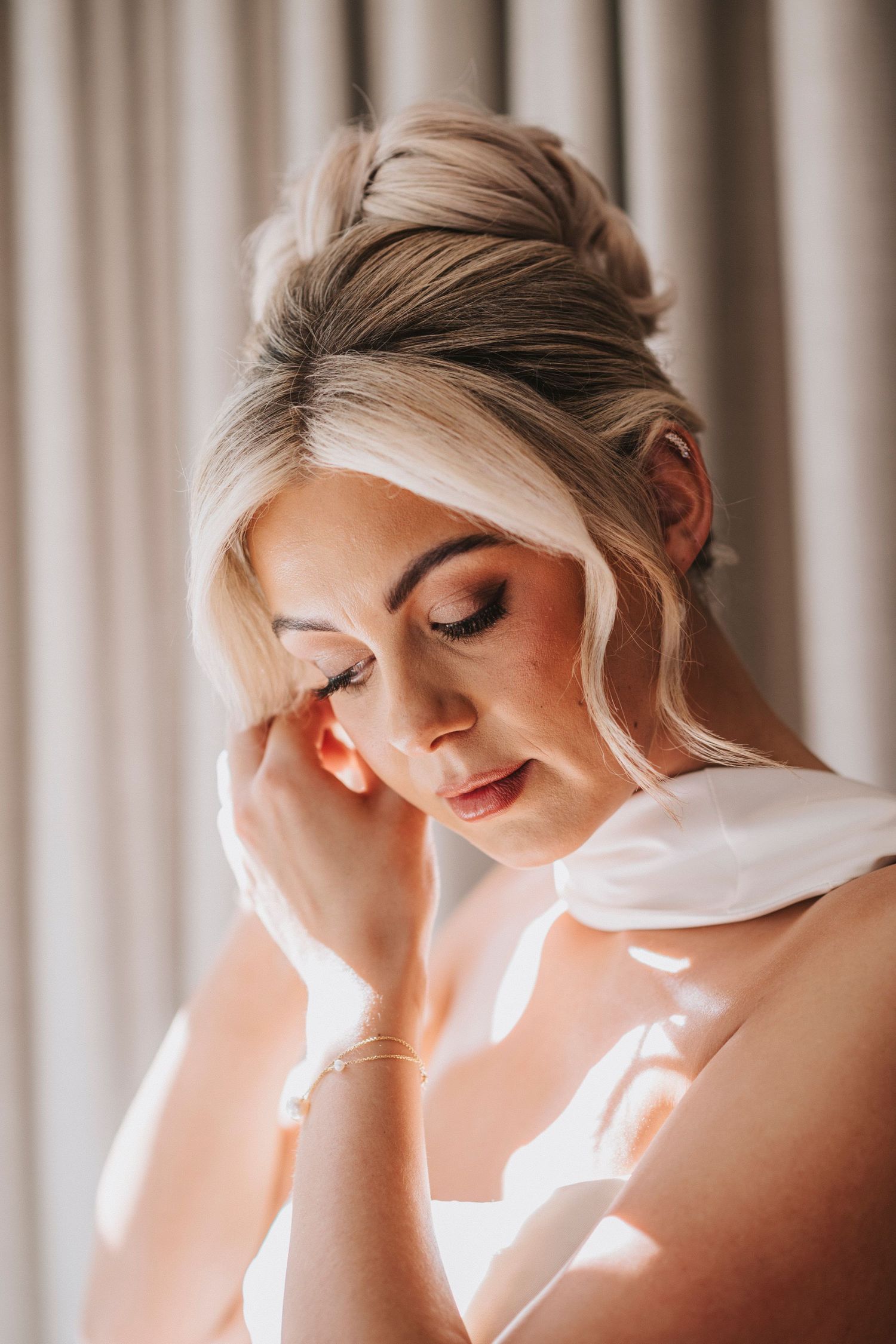 Soft natural light streams through curtains creating a dreamy atmosphere in a bridal portrait series.