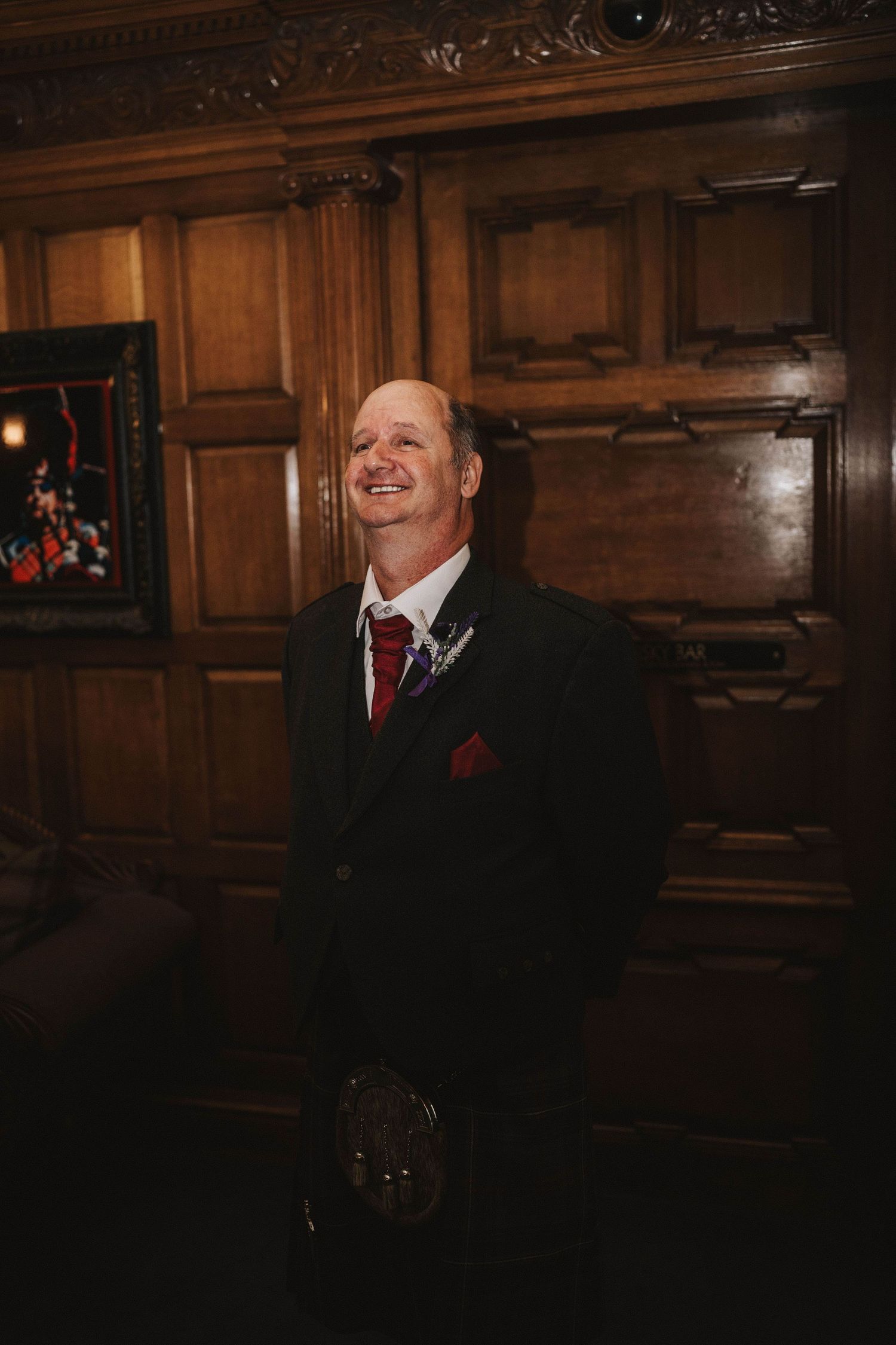 A joyful moment in formal attire captured against ornate wood paneling at an indoor venue.