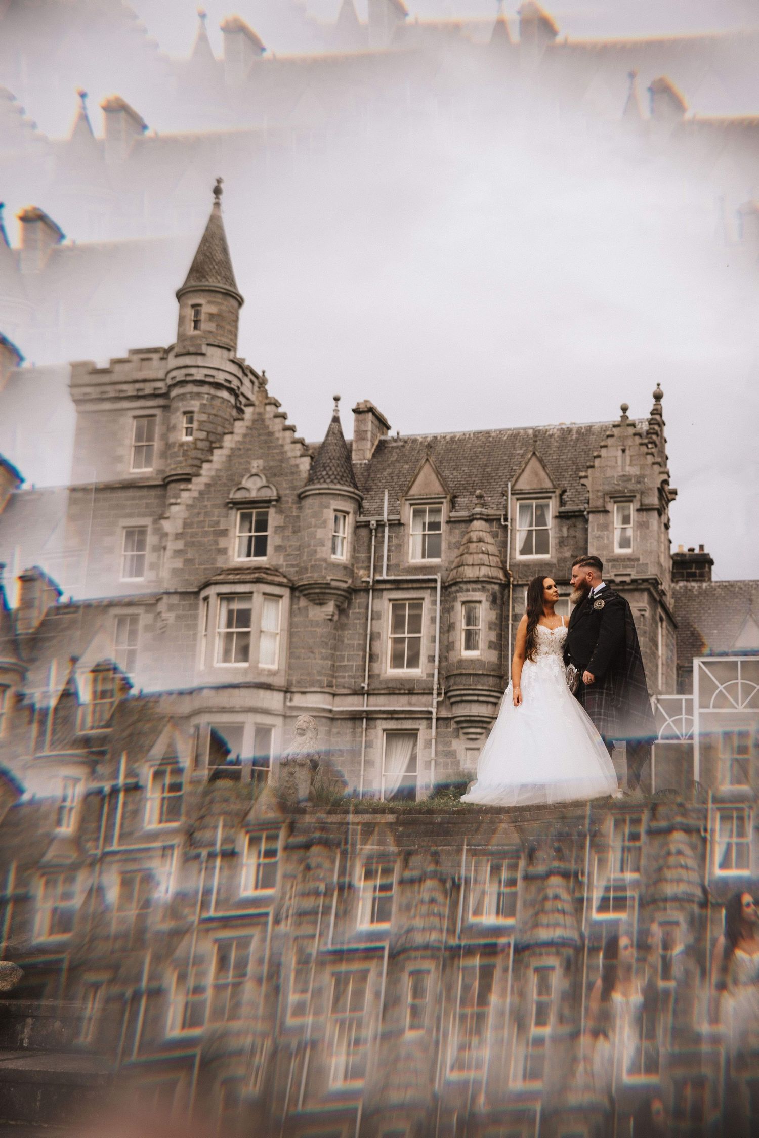 Wedding photography against a historic stone castle building with gothic architecture.