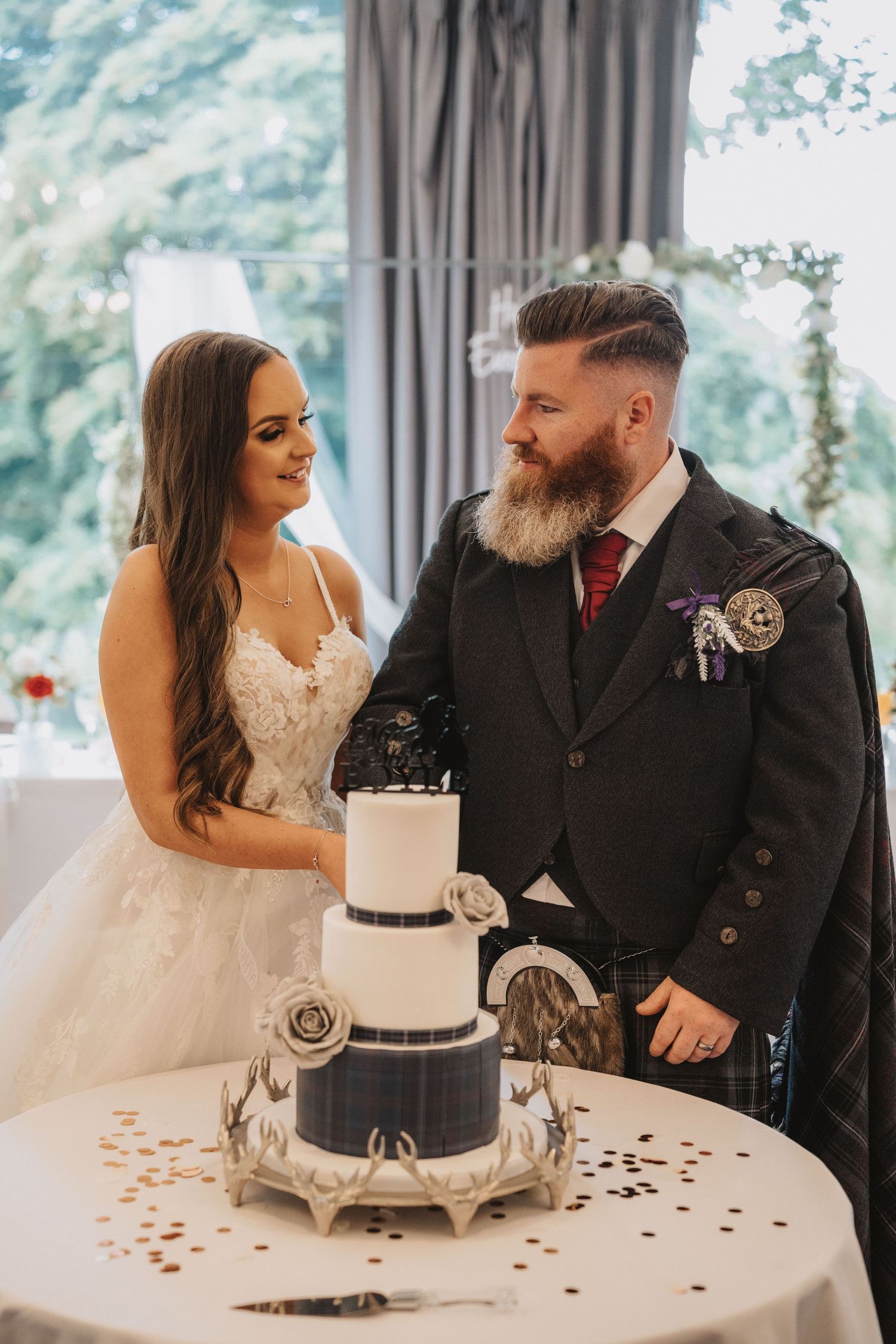 Wedding couple shares intimate moment by elegant black and white tiered cake at reception.