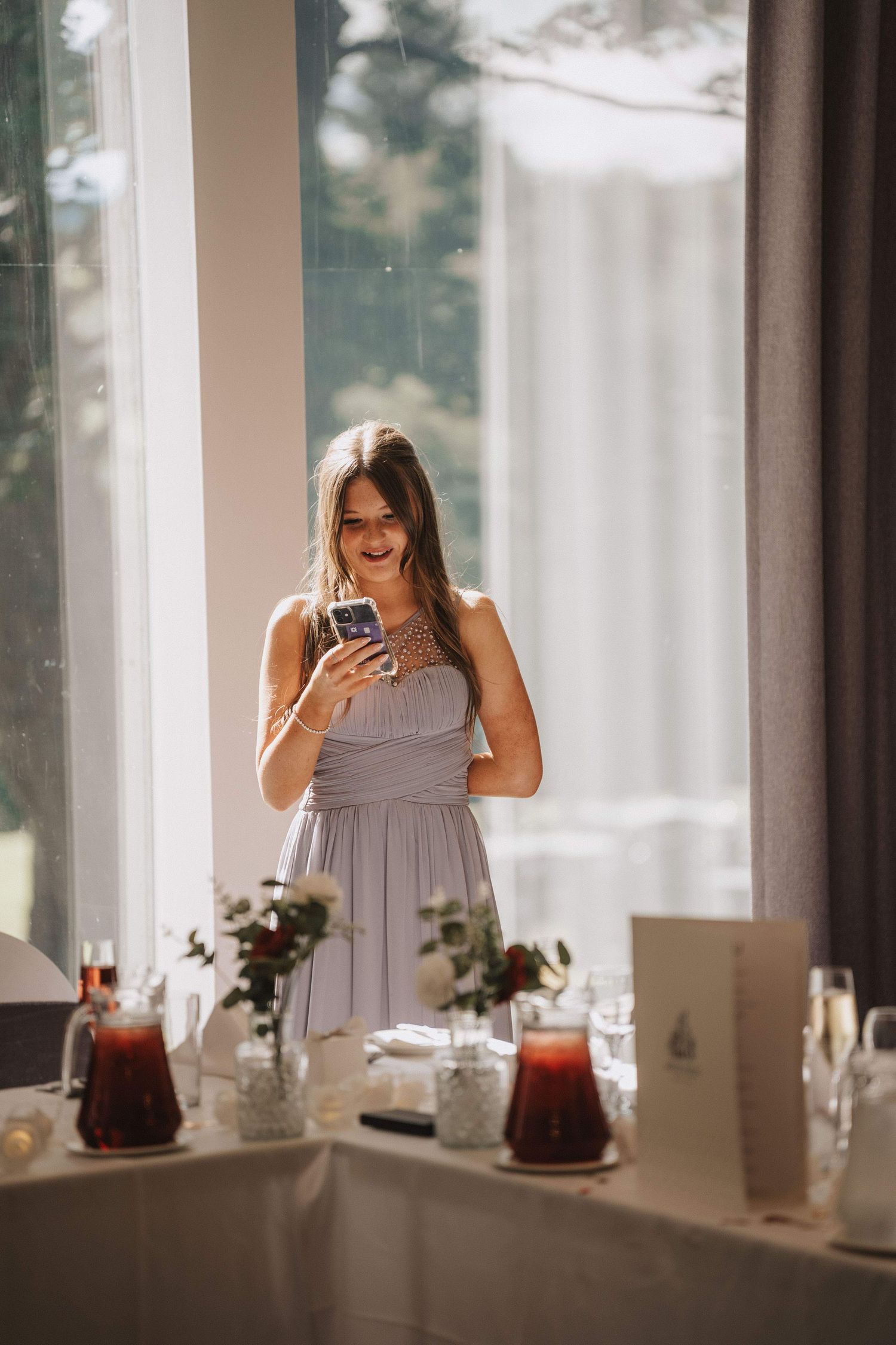 Candid moments captured at an elegant wedding reception with window light and table settings.