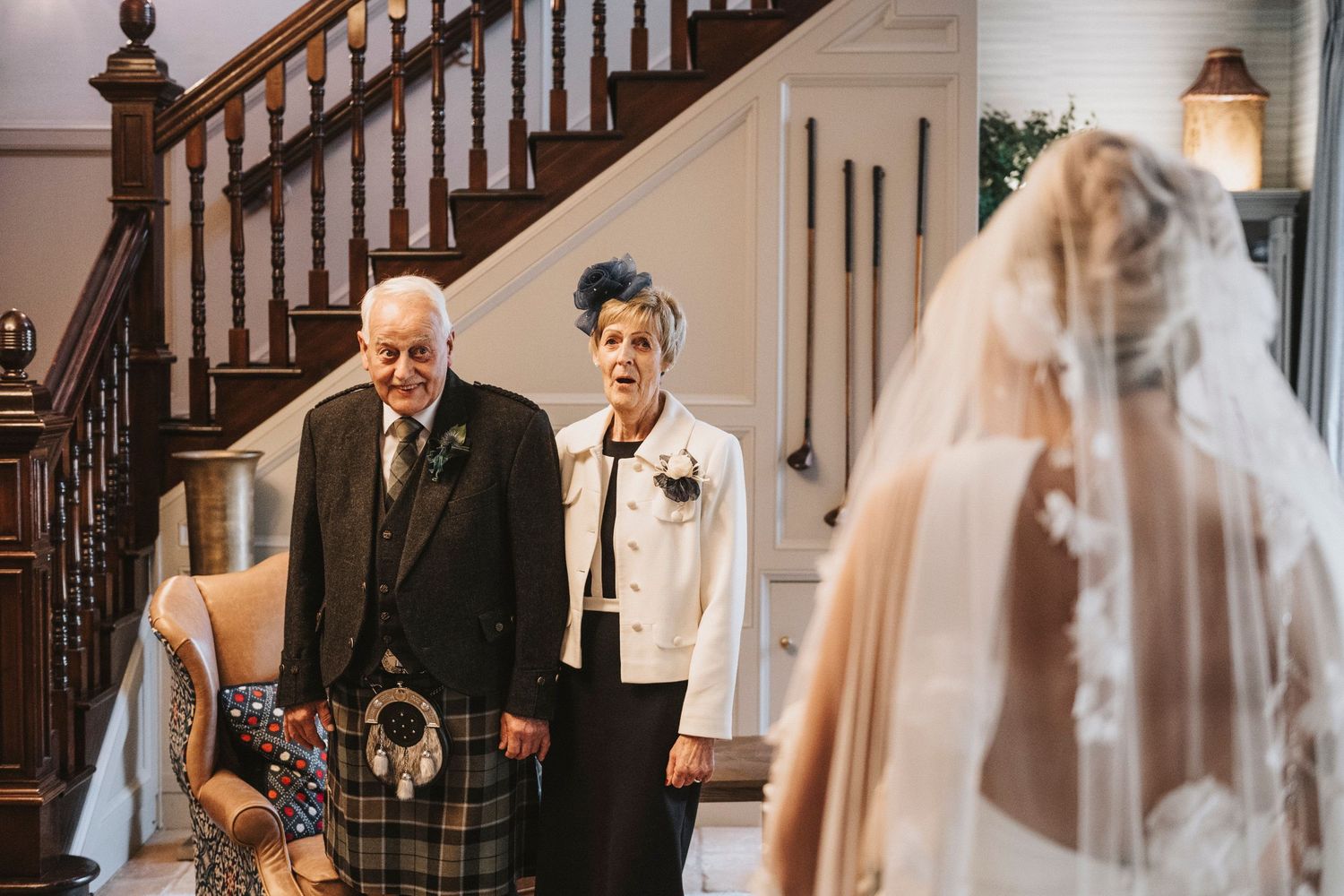 Wedding party members share emotional first look moments in an elegant staircase setting.