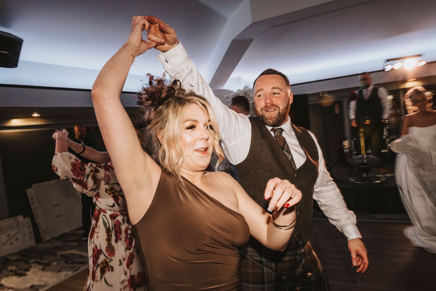 People dancing and celebrating at a lively party reception with dynamic lighting and movement.