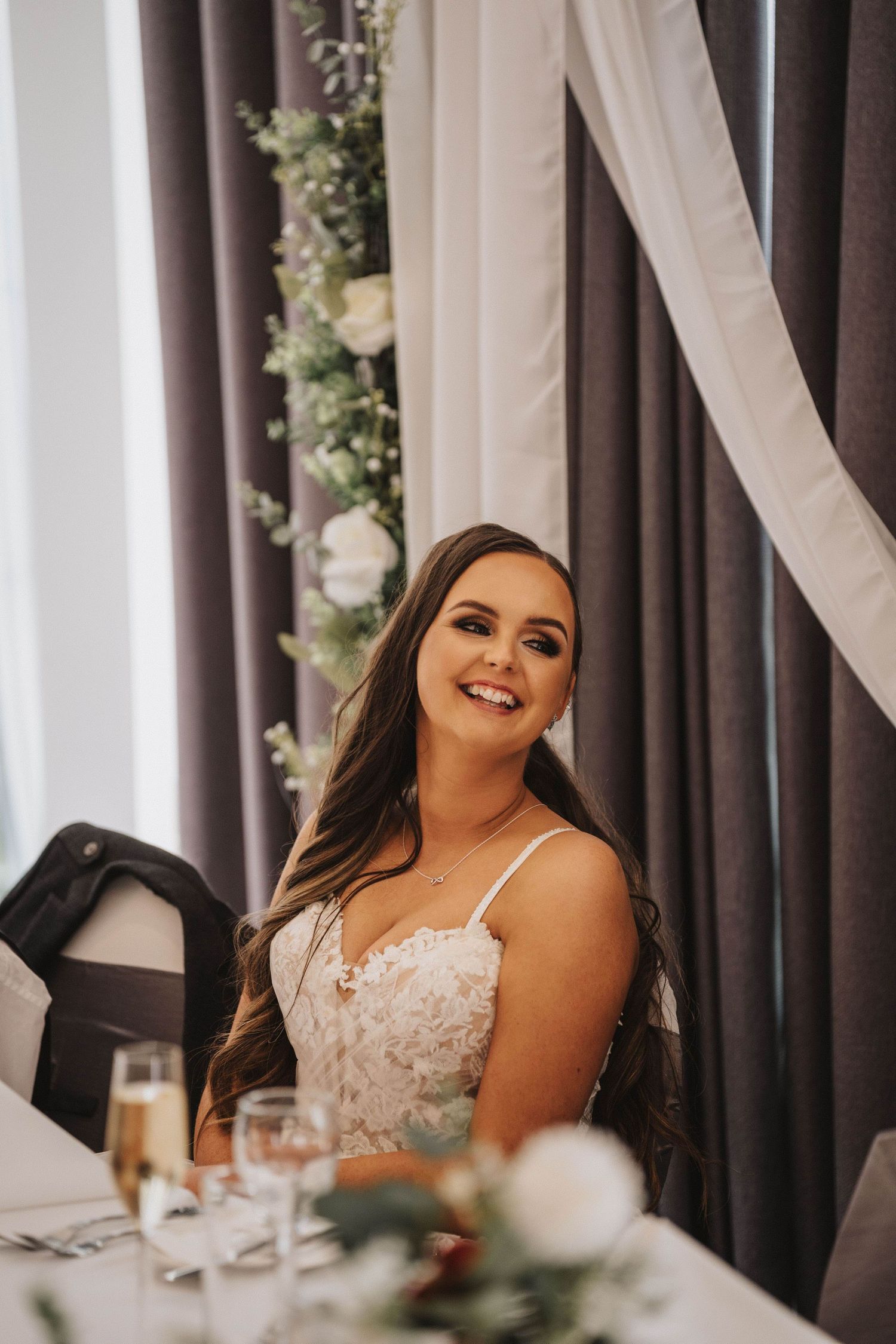 Candid reception photo with elegant decor featuring drapes and floral arrangements.