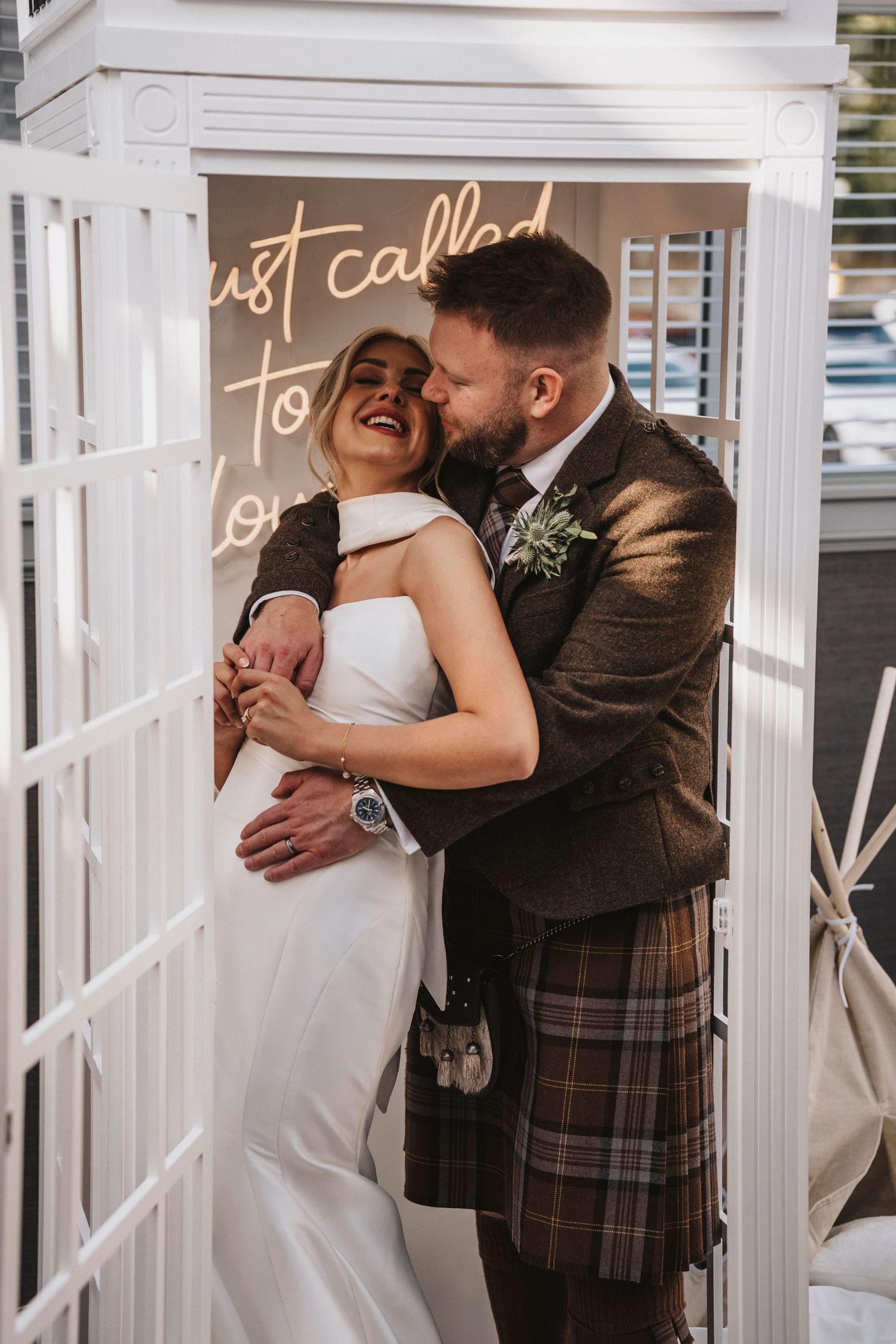 A romantic wedding moment captured between newlyweds sharing an intimate kiss in a white gazebo setting.