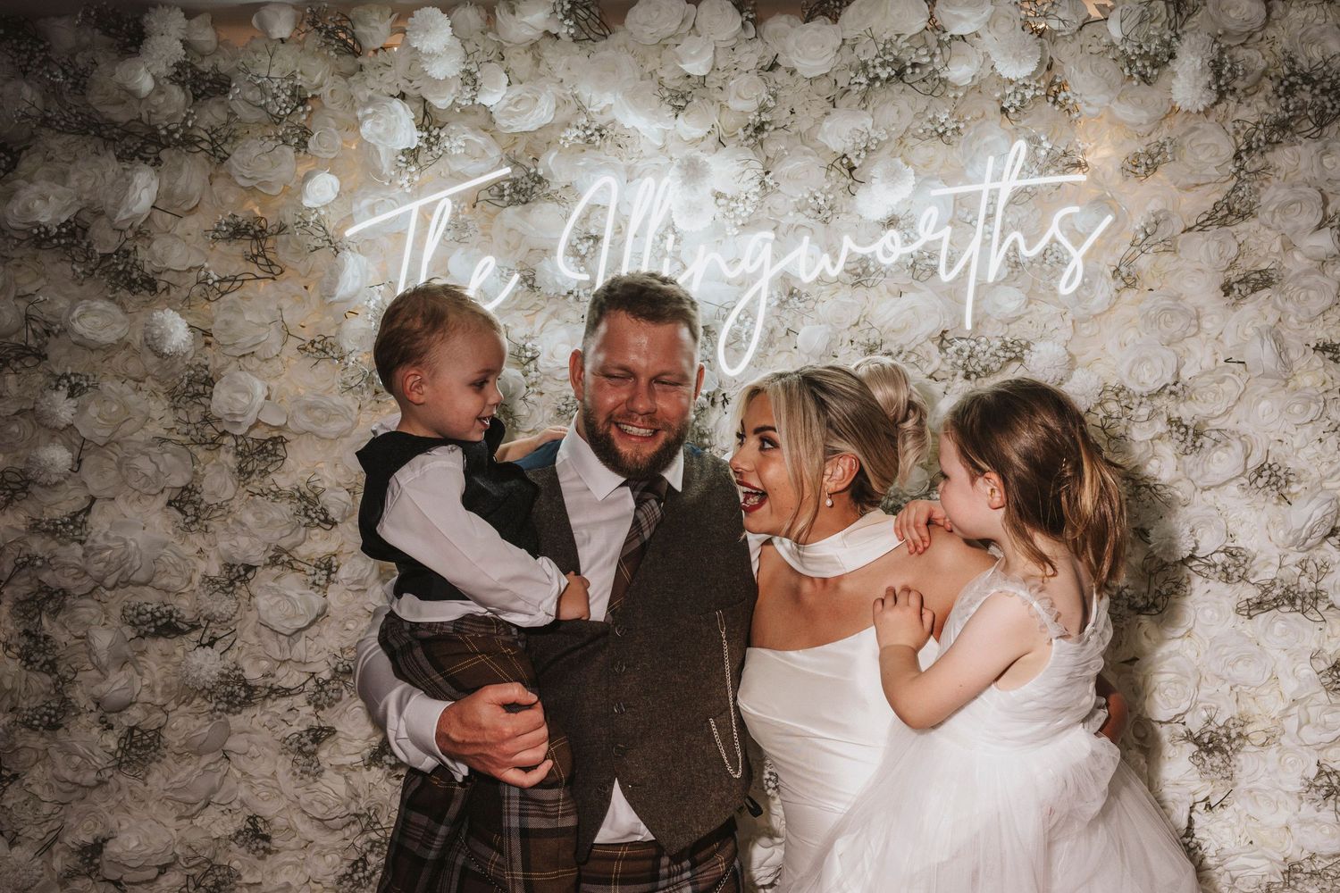 A romantic wedding couple shares intimate kisses in front of a rustic stone wall backdrop.