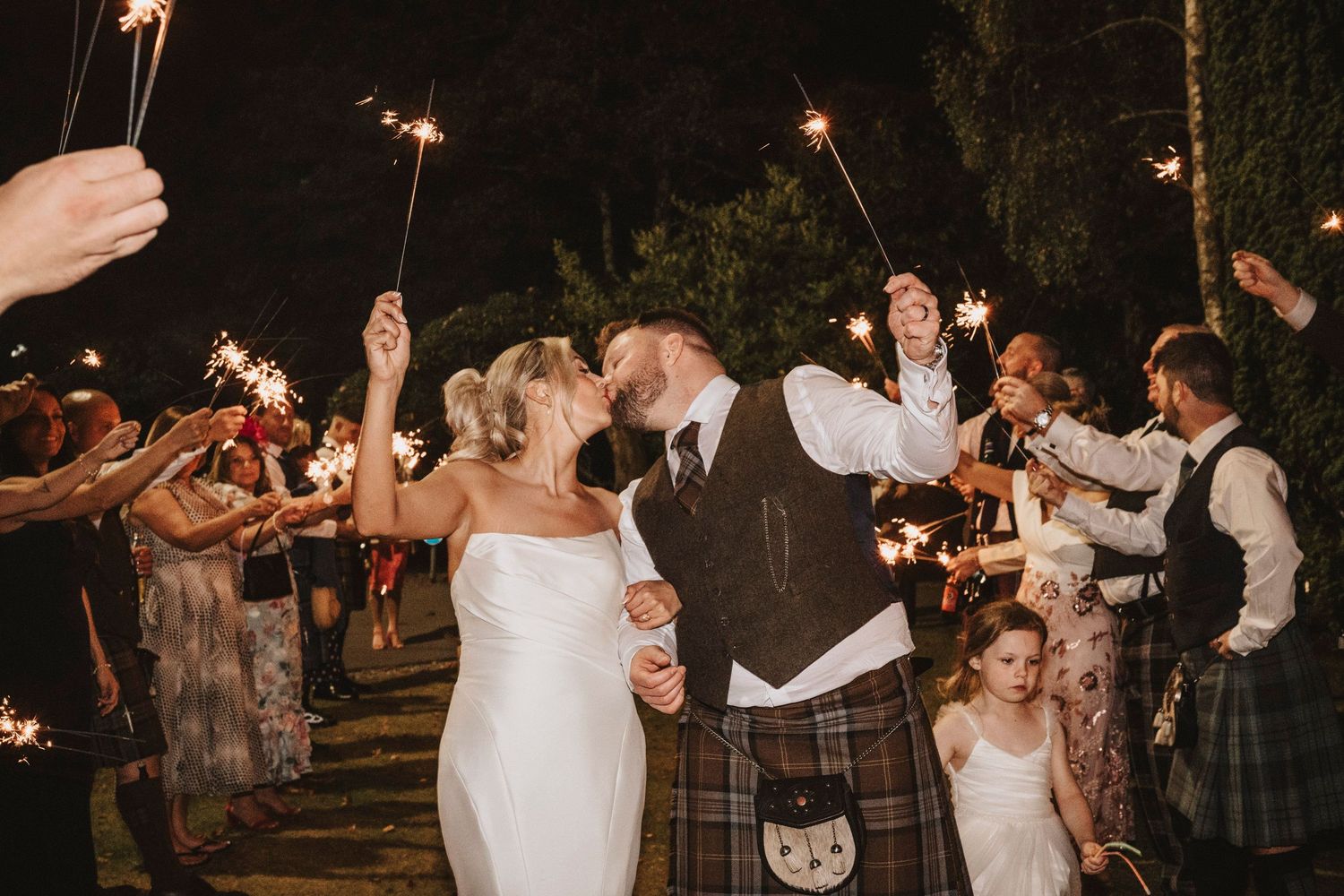 Guests dancing and celebrating at an outdoor evening wedding reception with string lights illuminating the festivities.