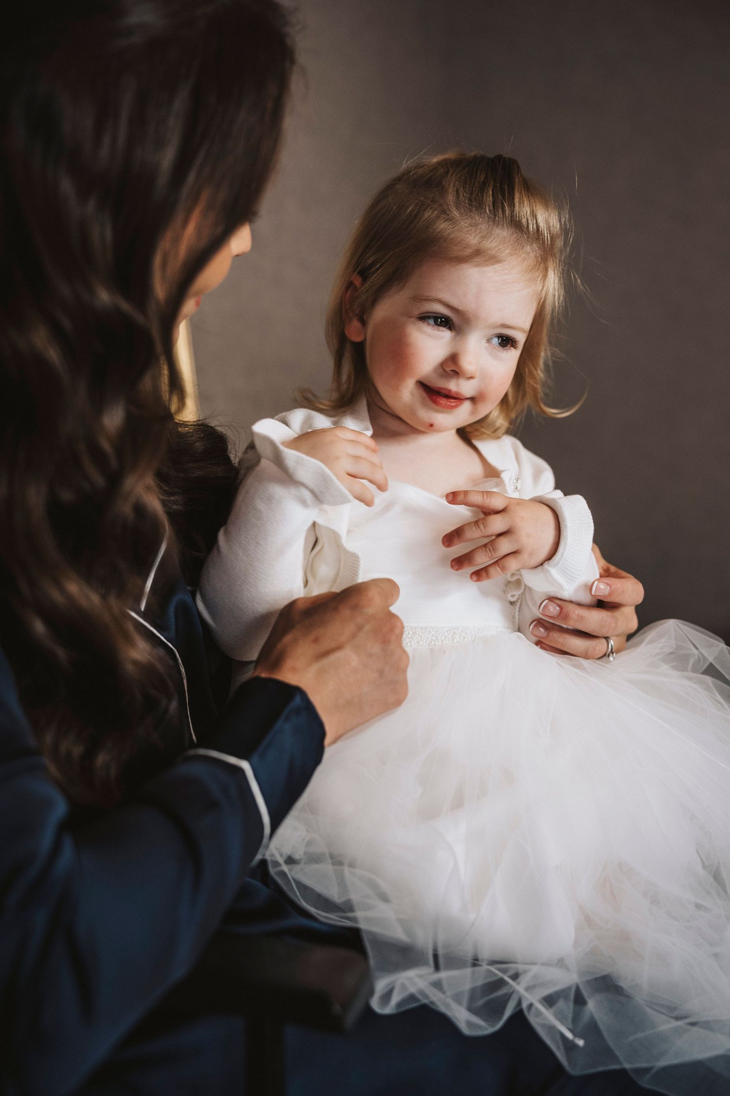 A series of photos showing a child in a white tulle dress being hugged and comforted by someone in a blue shirt.