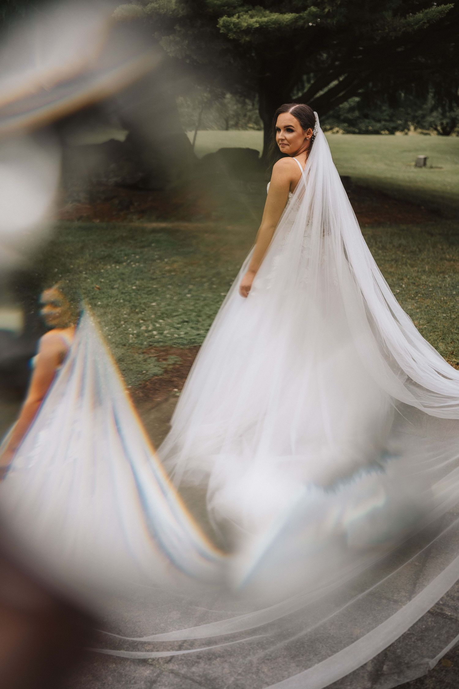 Artistic shot of flowing white wedding dress and veil caught in motion outdoors.
