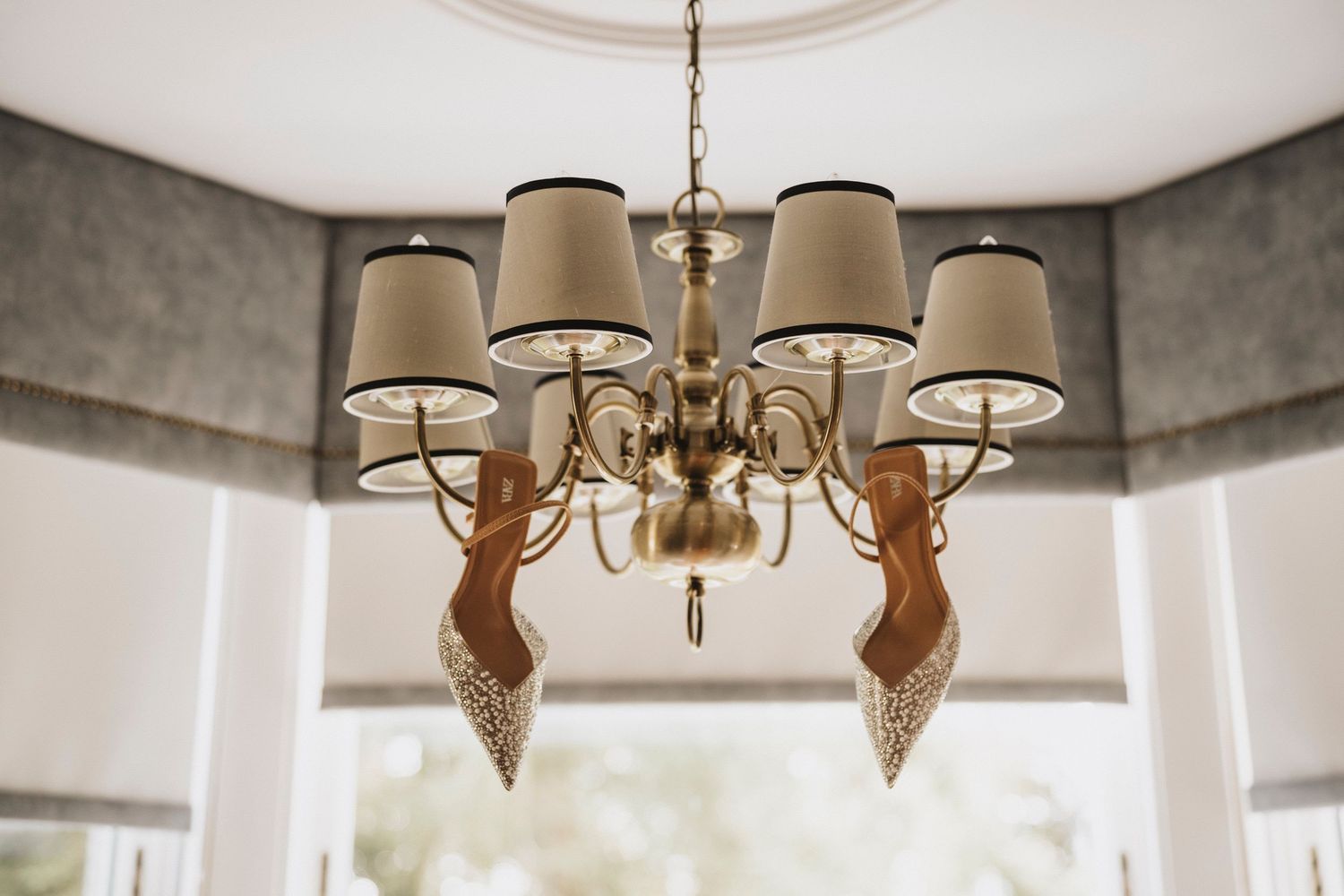 A modern chandelier with beige drum shades hangs from a white ceiling in an elegant interior setting.