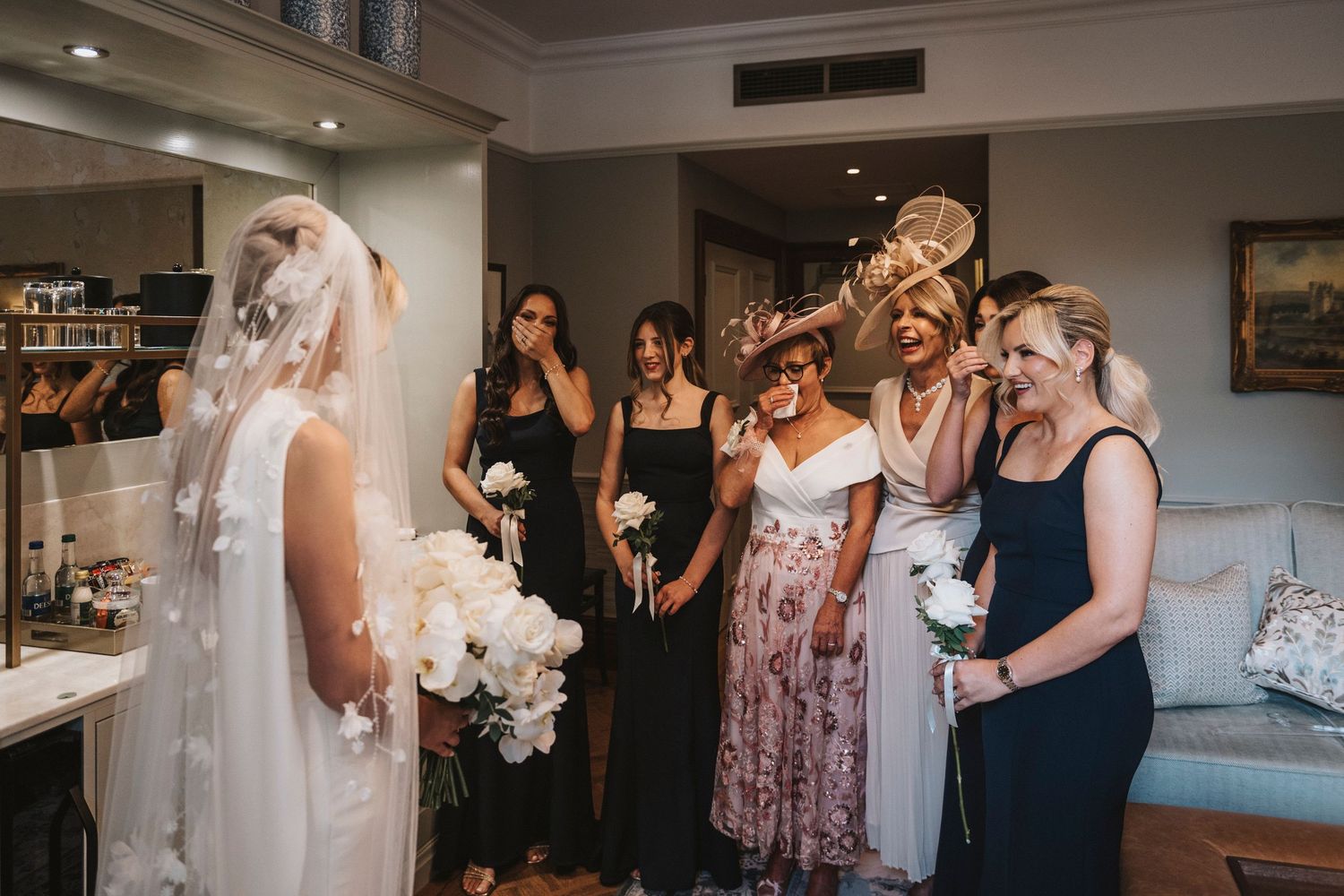 A bride and bridesmaids share emotional moments while getting ready in a hotel room before the wedding ceremony.