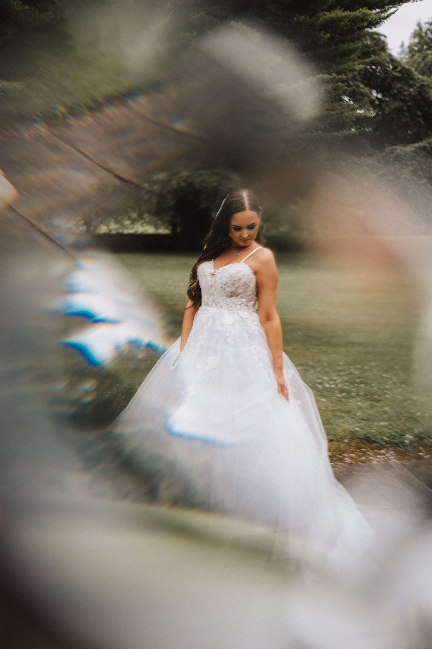 White wedding dress flows elegantly against a natural outdoor backdrop with blurred artistic motion effects.